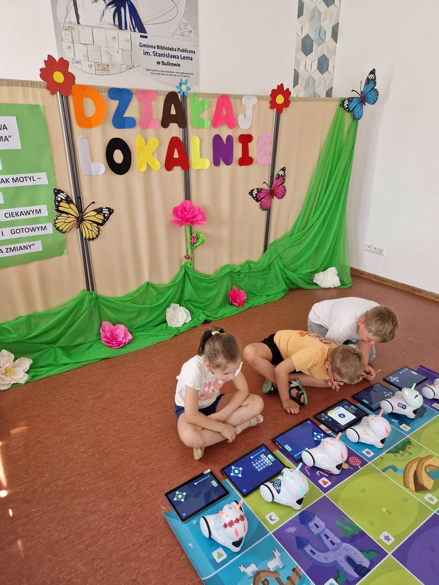Na zdjęciu znajdują się dzieci, które sterują robotami w ramach projektu Działaj Lokalnie.