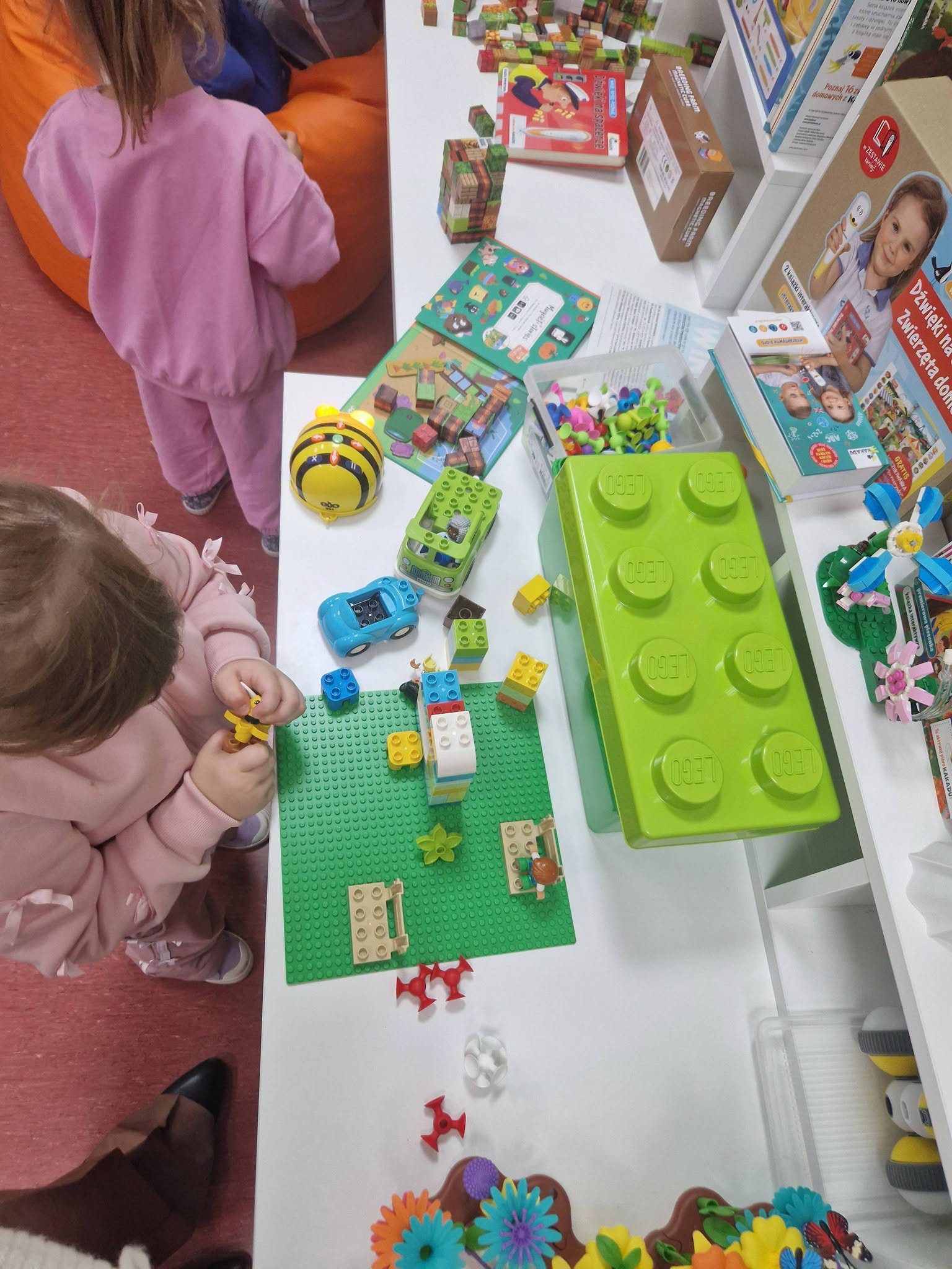 Zdjęcie przedstawia układanie przez dzieci klocków lego.