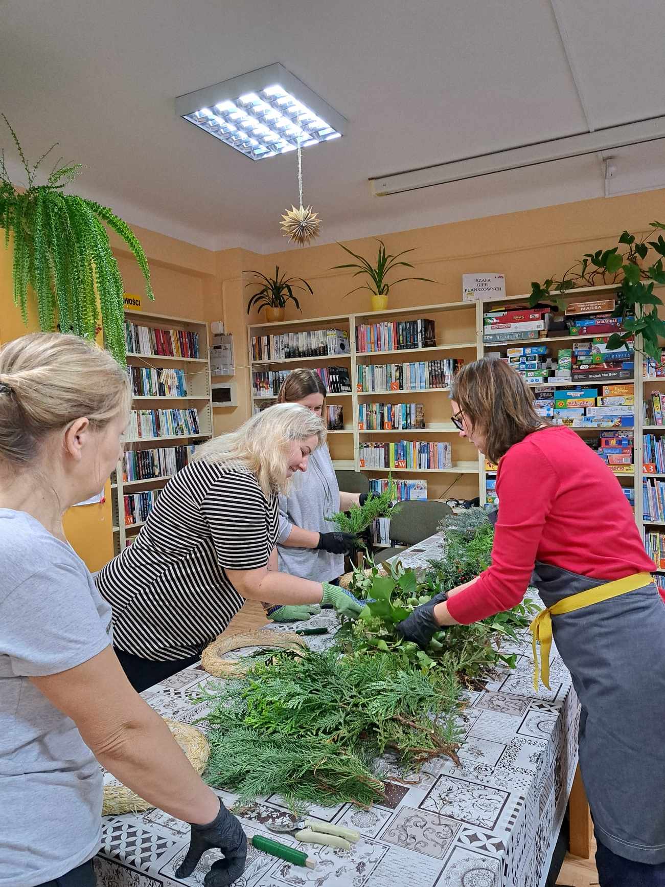 Grupa kobiet tworzy wianki świąteczne.