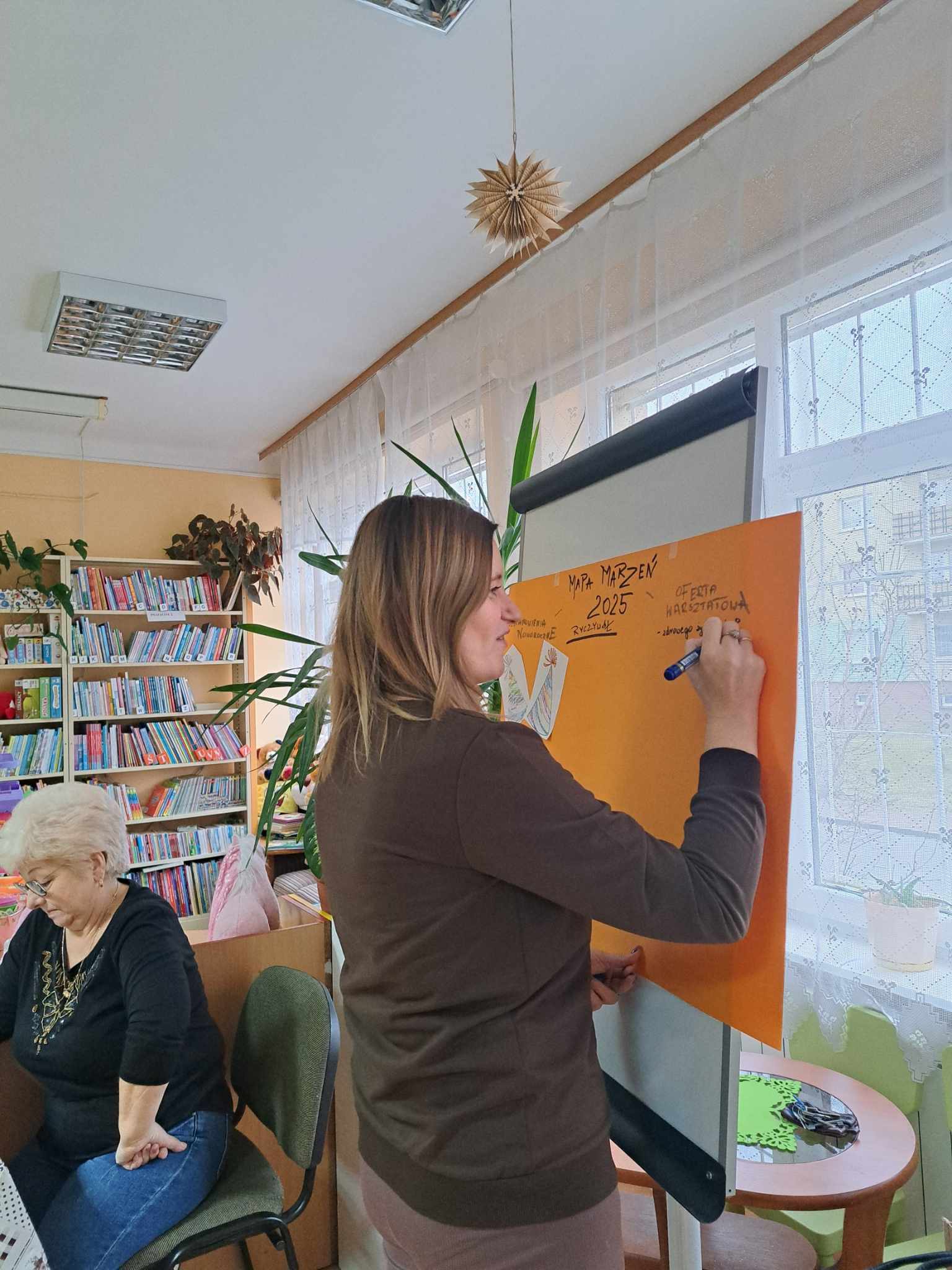 Kobieta zapisuje na kartce marzenia dotyczące Pracowni Orange.