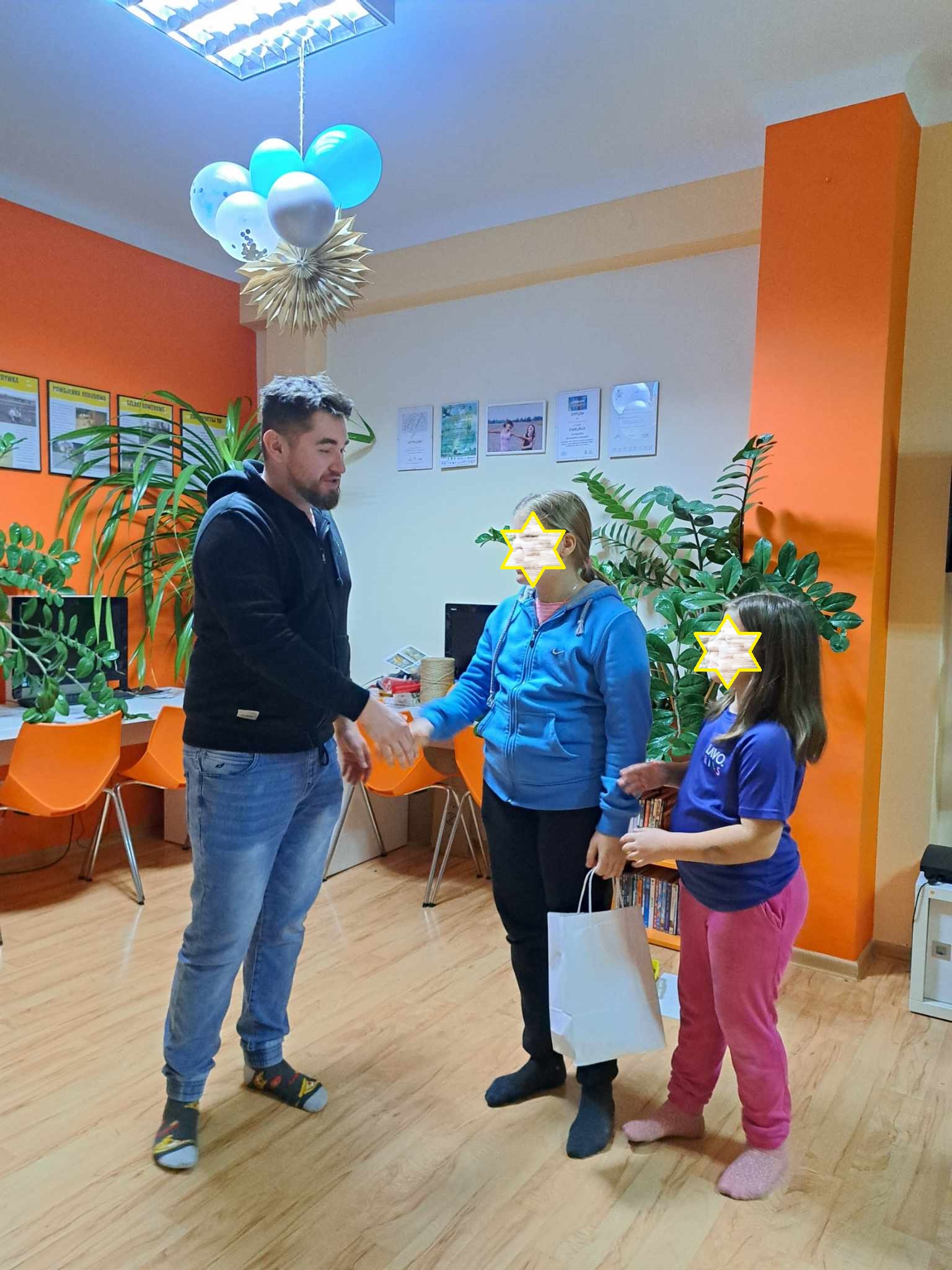 Dwie dziewczynki obierają nagrody za odpowiedzi w konkursie.