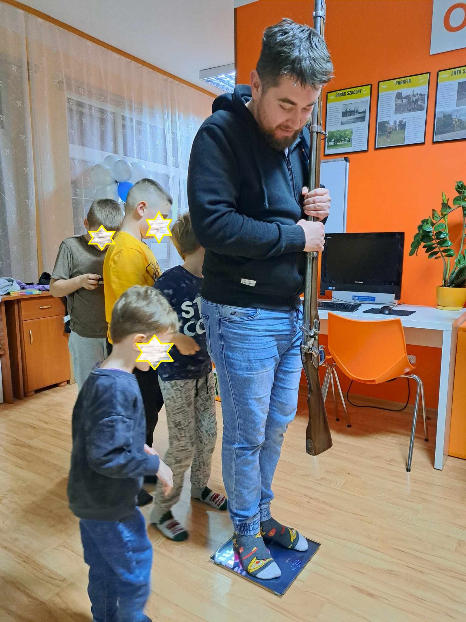 Mężczyzna stoi na wadze trzymając muszkiet w dłoniach.