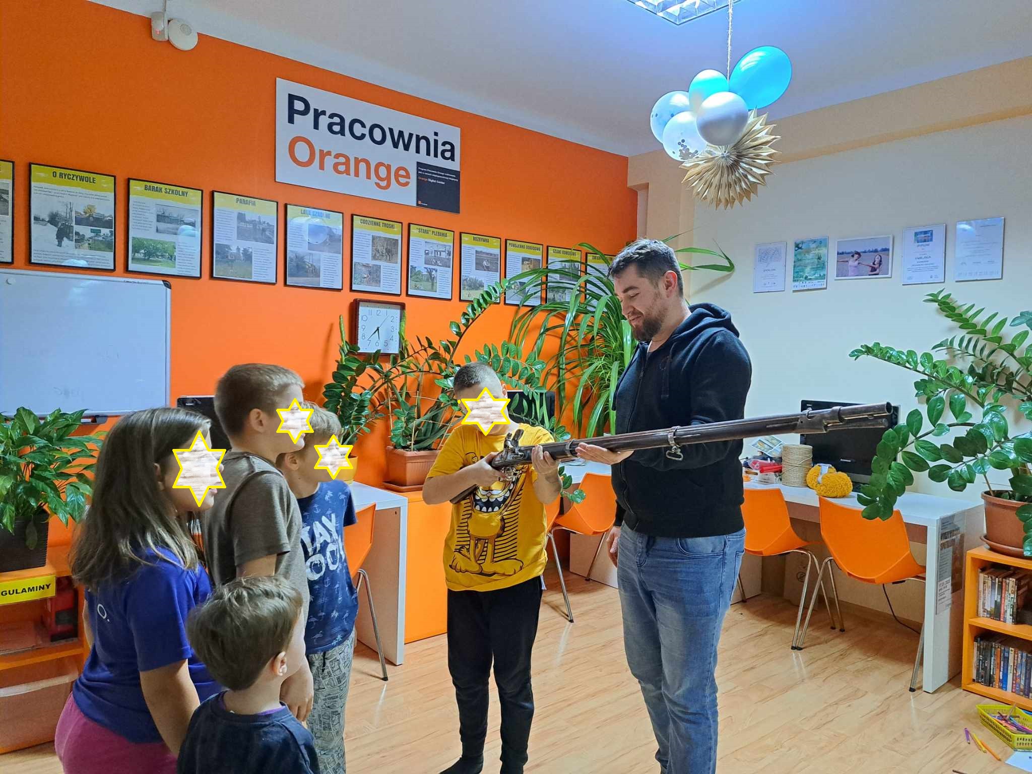 Grupa dzieci ogląda muszkiet trzymany przez mężczyznę.