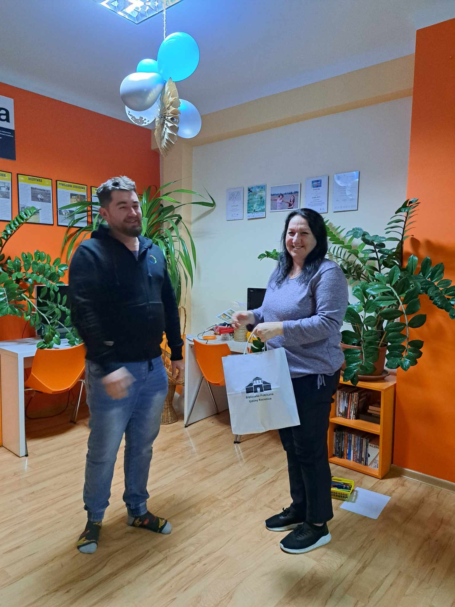 Kobieta odbiera nagrodę za odpowiedź w konkursie, w papierowej torbie