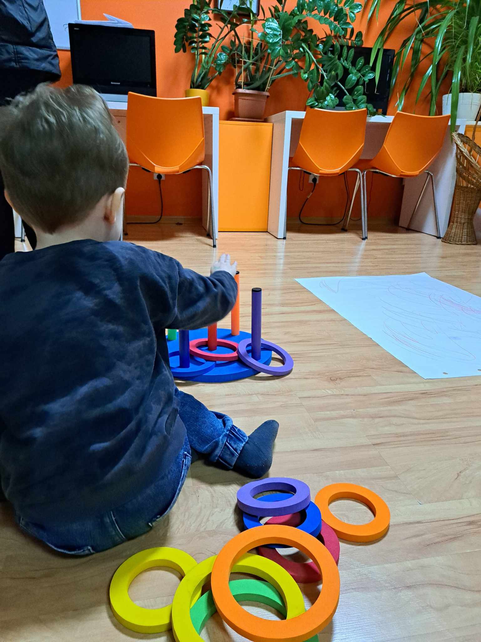 Chłopiec siedzi na podłodze w pracowni i bawi się.