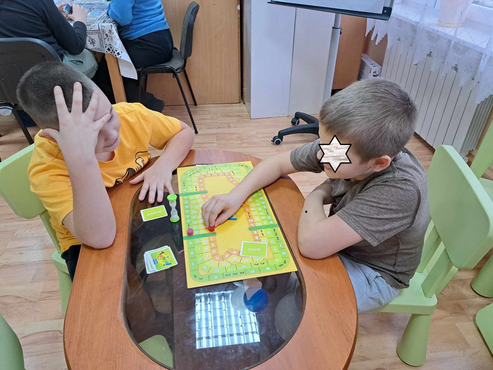 Grupa dzieci podczas gry w planszówki.