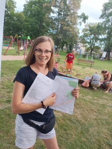 Pani trzyma w rękach mapkę z grą TRInO