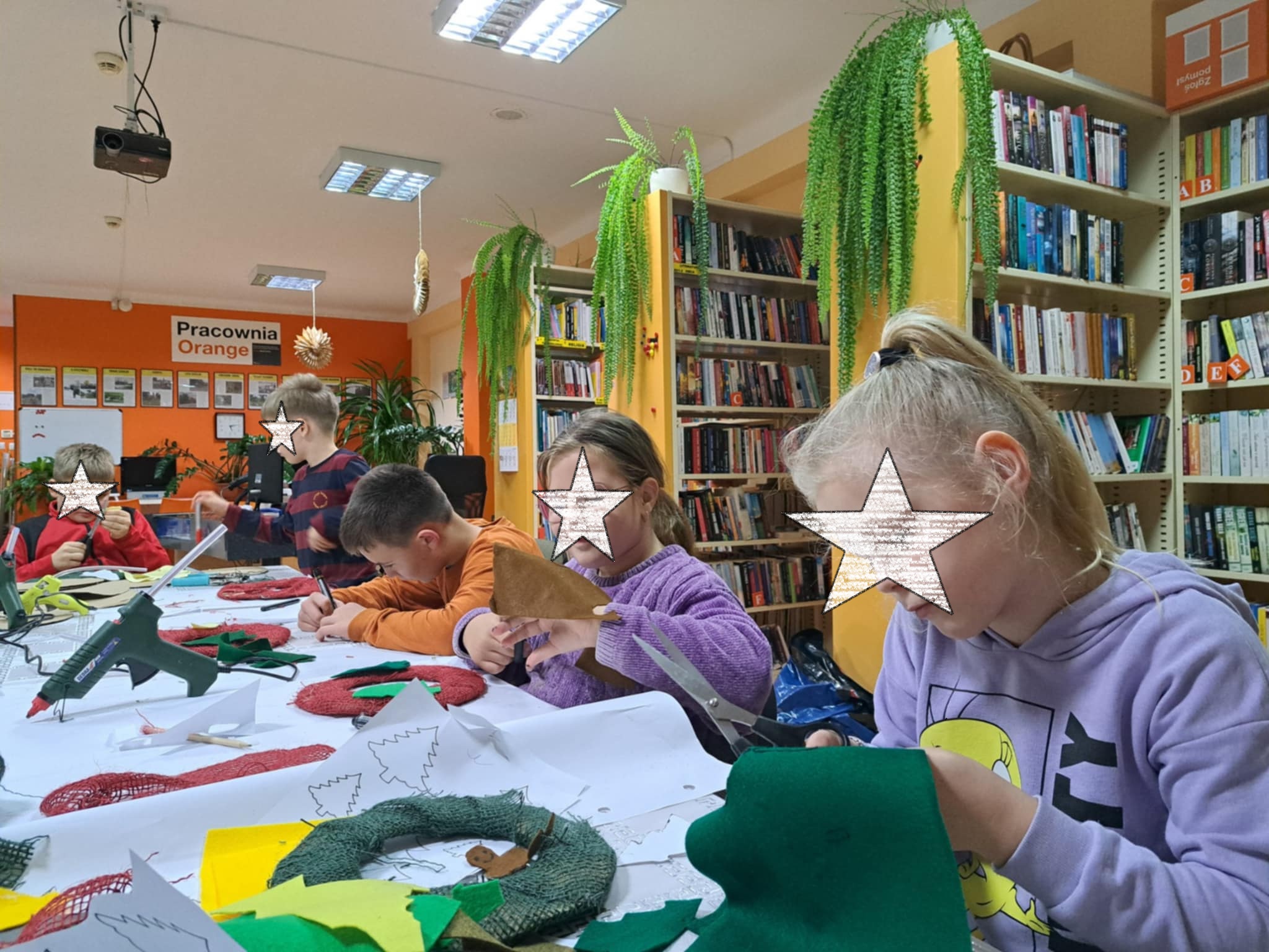 Dzieci przygotowujące ozdoby świąteczne przy stole.