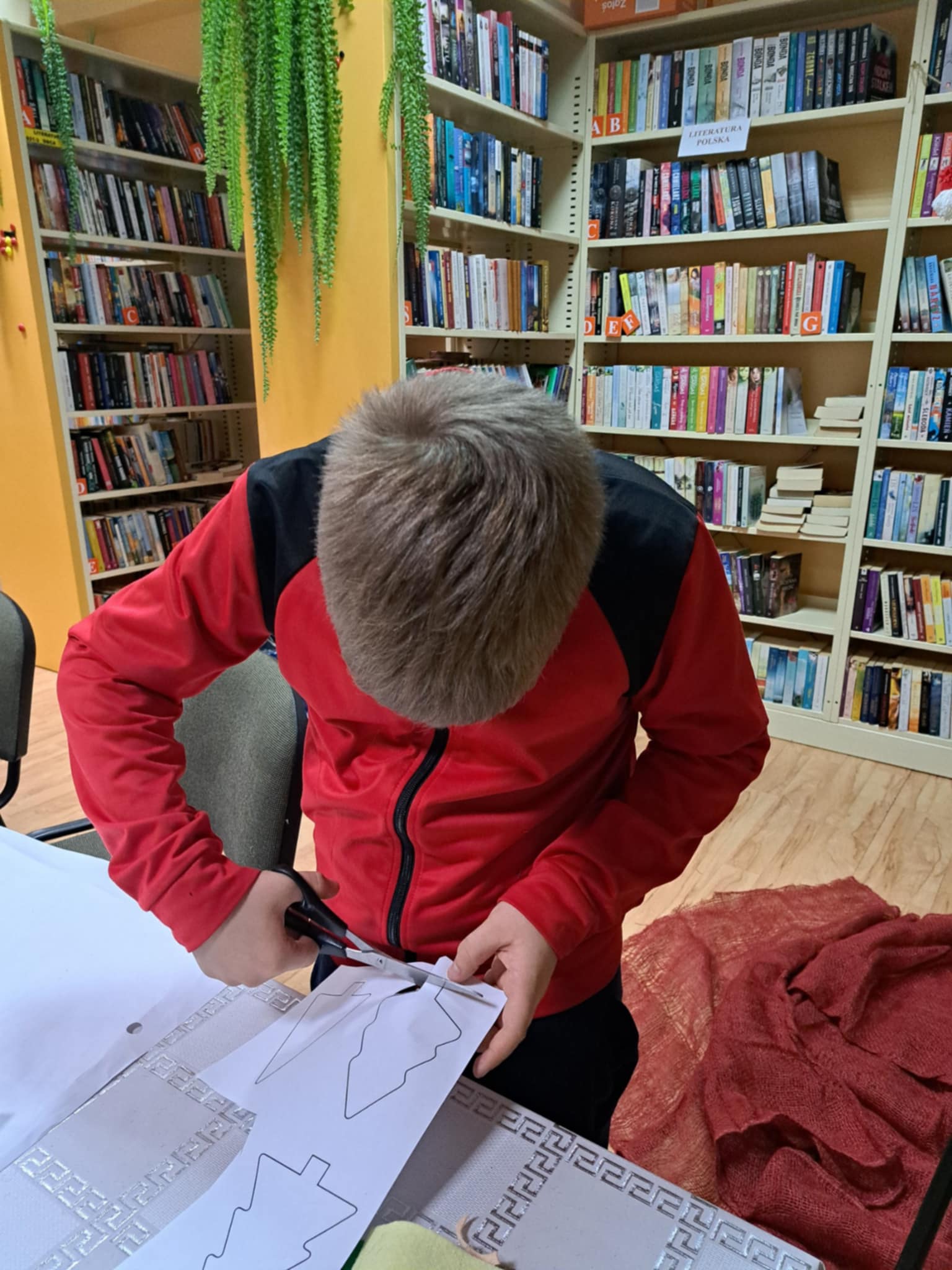 Chłopiec wycinający choinkę z papieru.