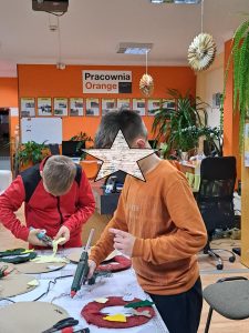 Dwóch chłopców przy stole klei za pomocą pistoletu na gorąco.