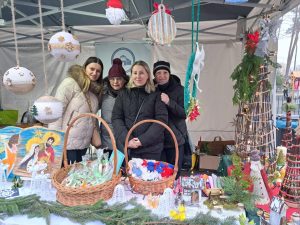 Cztery panie stoja pod namiotem. za stołem z dekoracjami światecznymi.