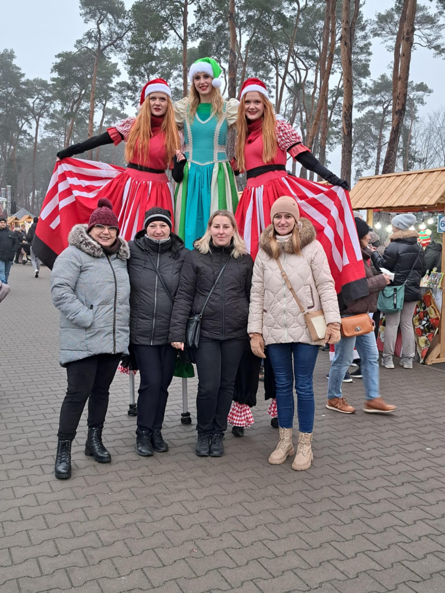 Kobiety stojące na tle osób na szczudłach przebranych za elfy.