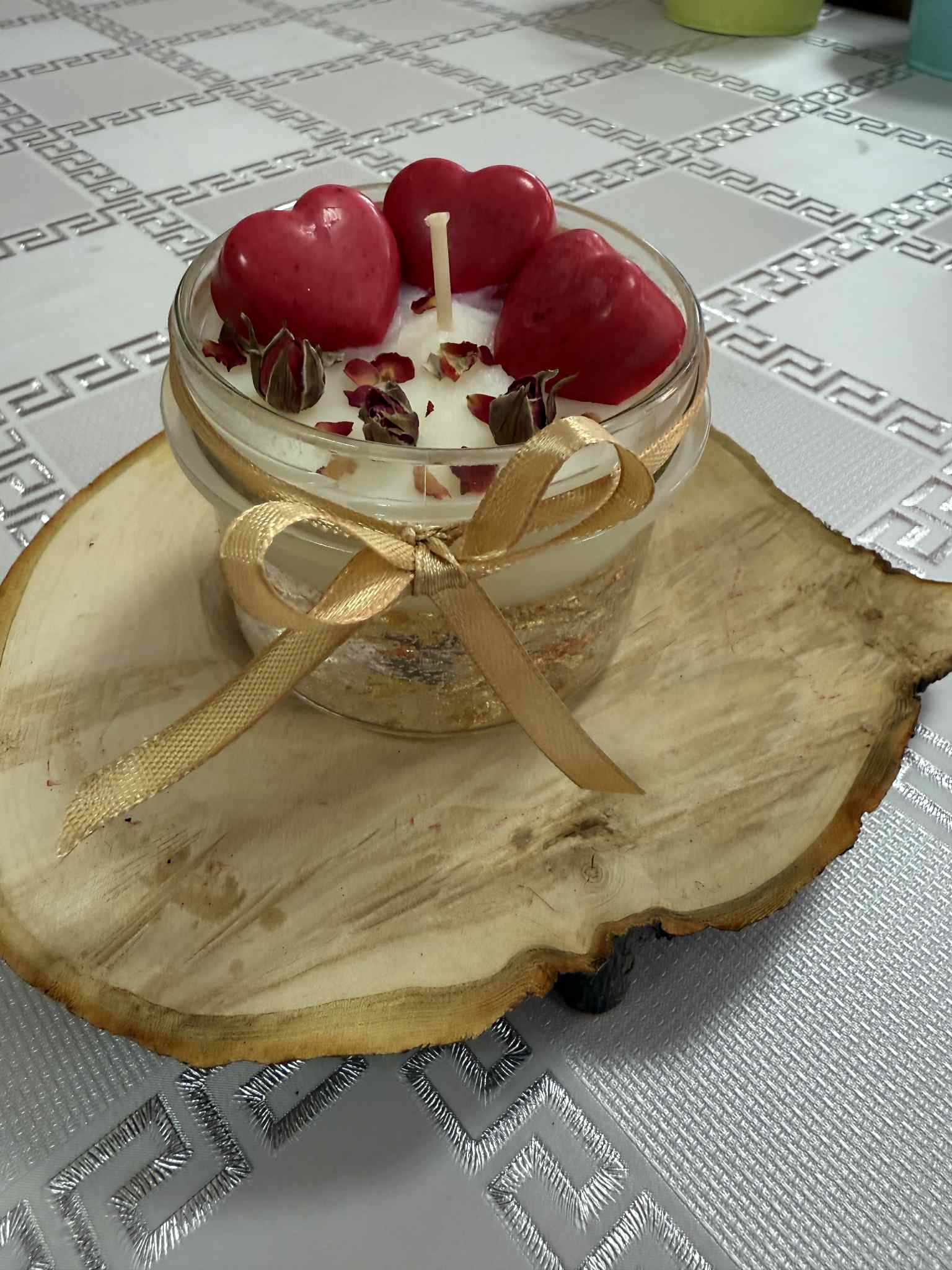 Świeca sojowa w słoiczku postawiona na plastrze drewna.