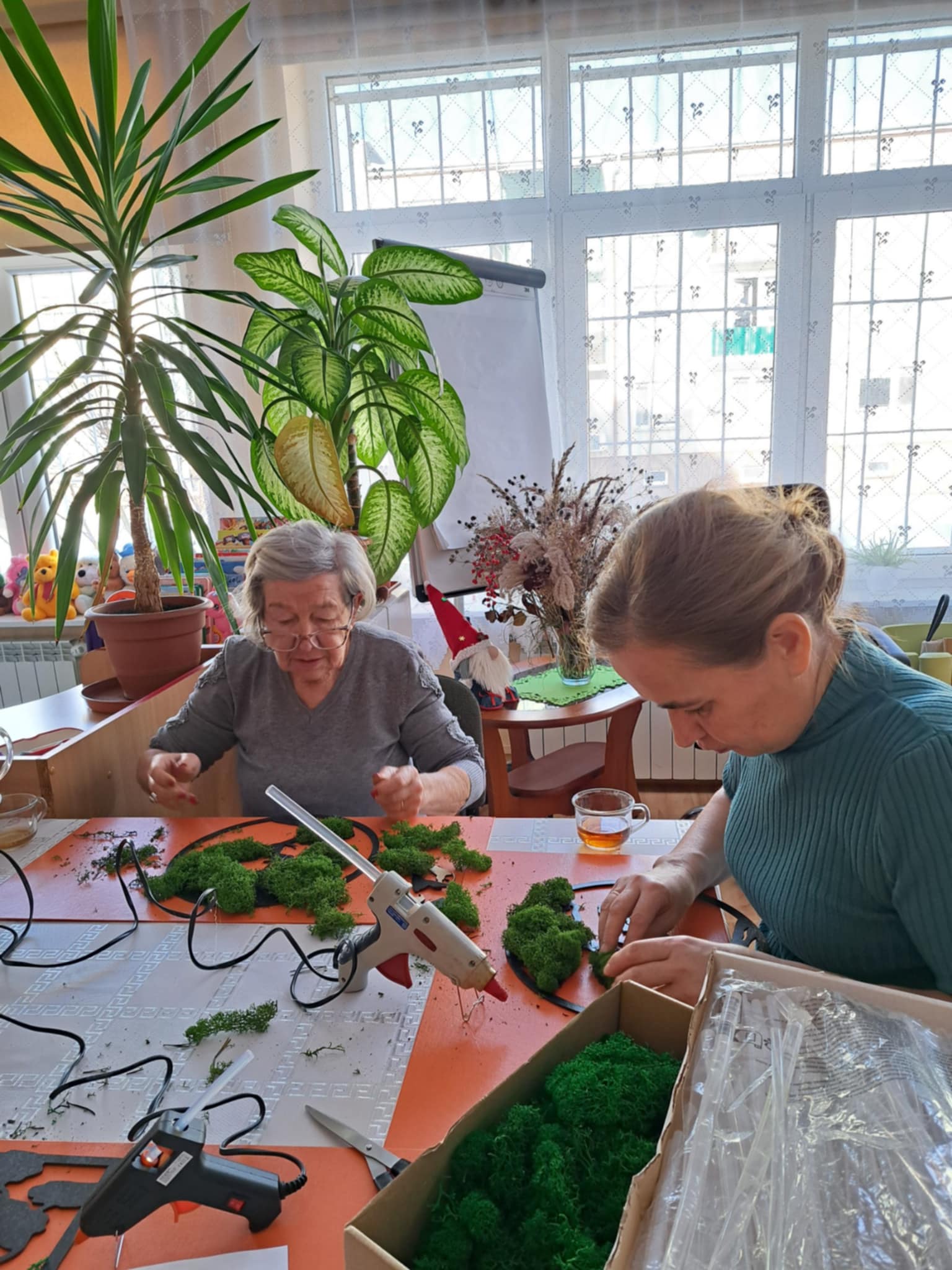 Kobiety siedzące przy stole klejące mech do drzewka.