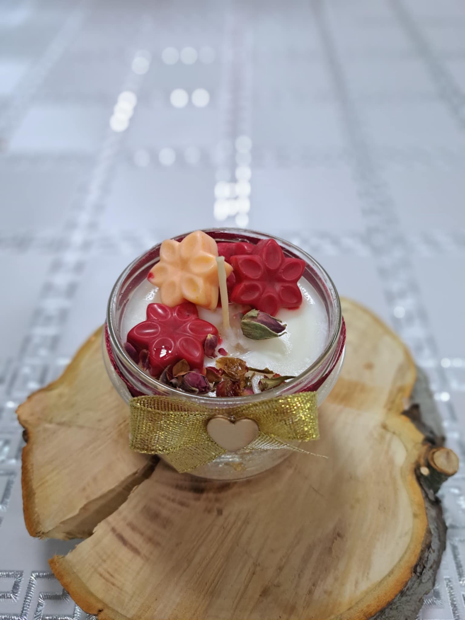 Świeca sojowa w słoiczku na plastrze drewna.