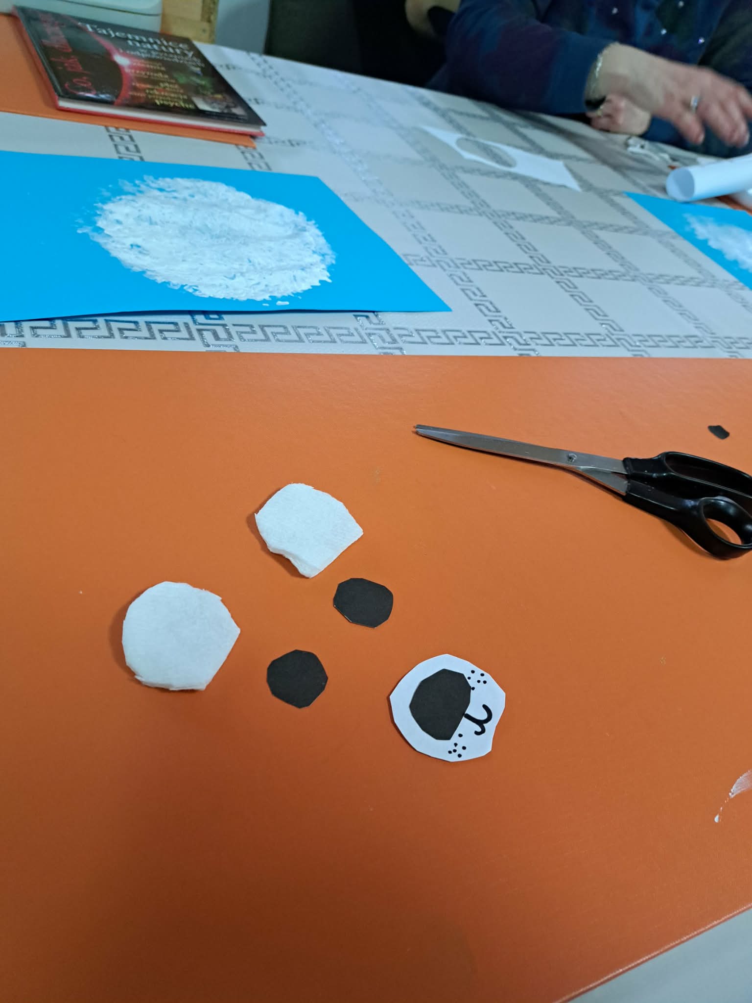 Na pomarańczowej podkładce leżą elementy misiowego portretu.