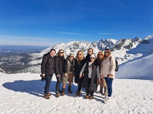 Osiem kobiet stoi na ośnieżonym szczycie górskim
