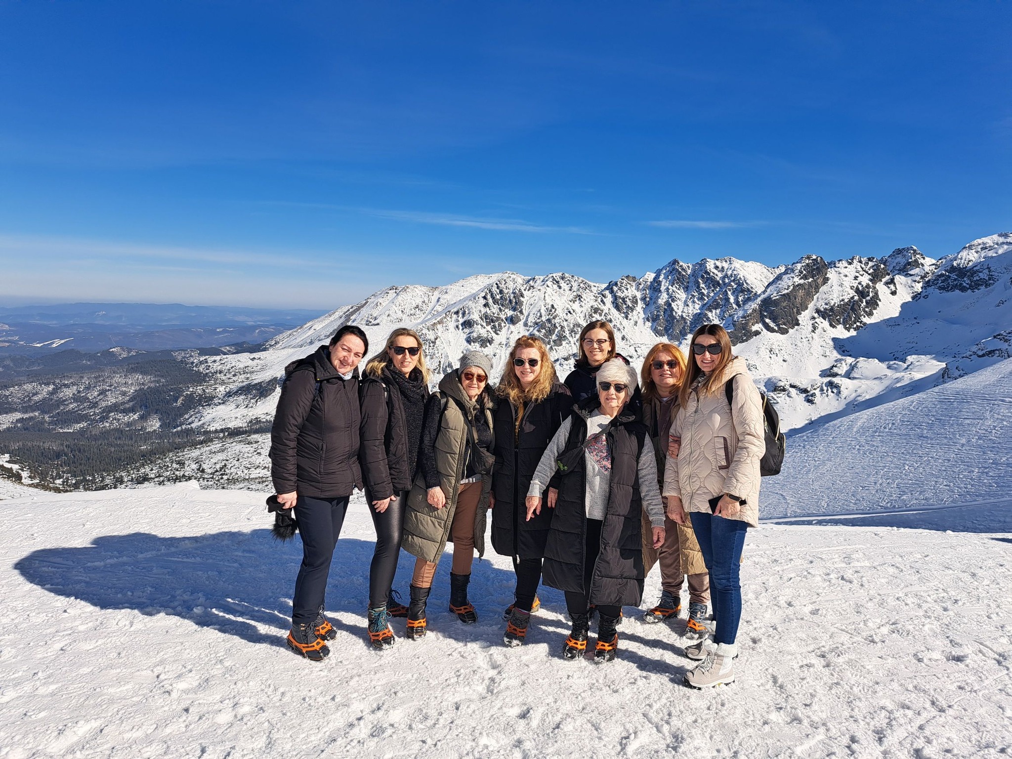 Osiem kobiet stoi na ośnieżonym szczycie górskim