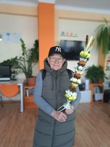 Pani stoi i trzyma w rękach palmę wielkanocną.