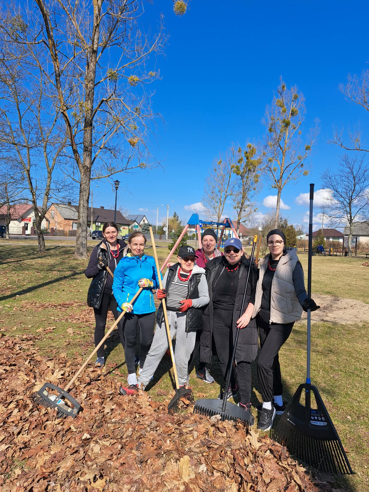 Grupa kobiet stoi z grabiami na rynku.
