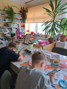 Dwaj chłopcy siedzą przy stole i pracują z długopisami 3D