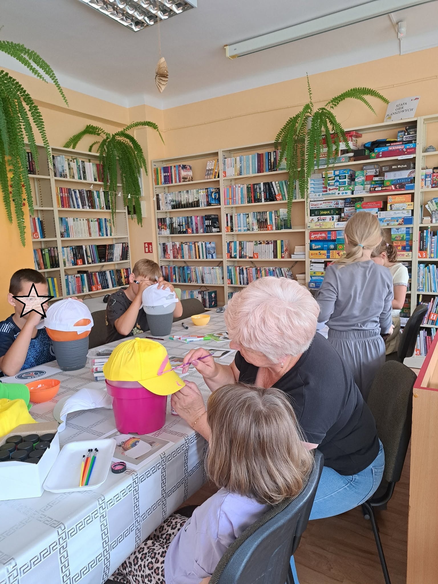 Dzieci malują czapeczki z daszkiem.
