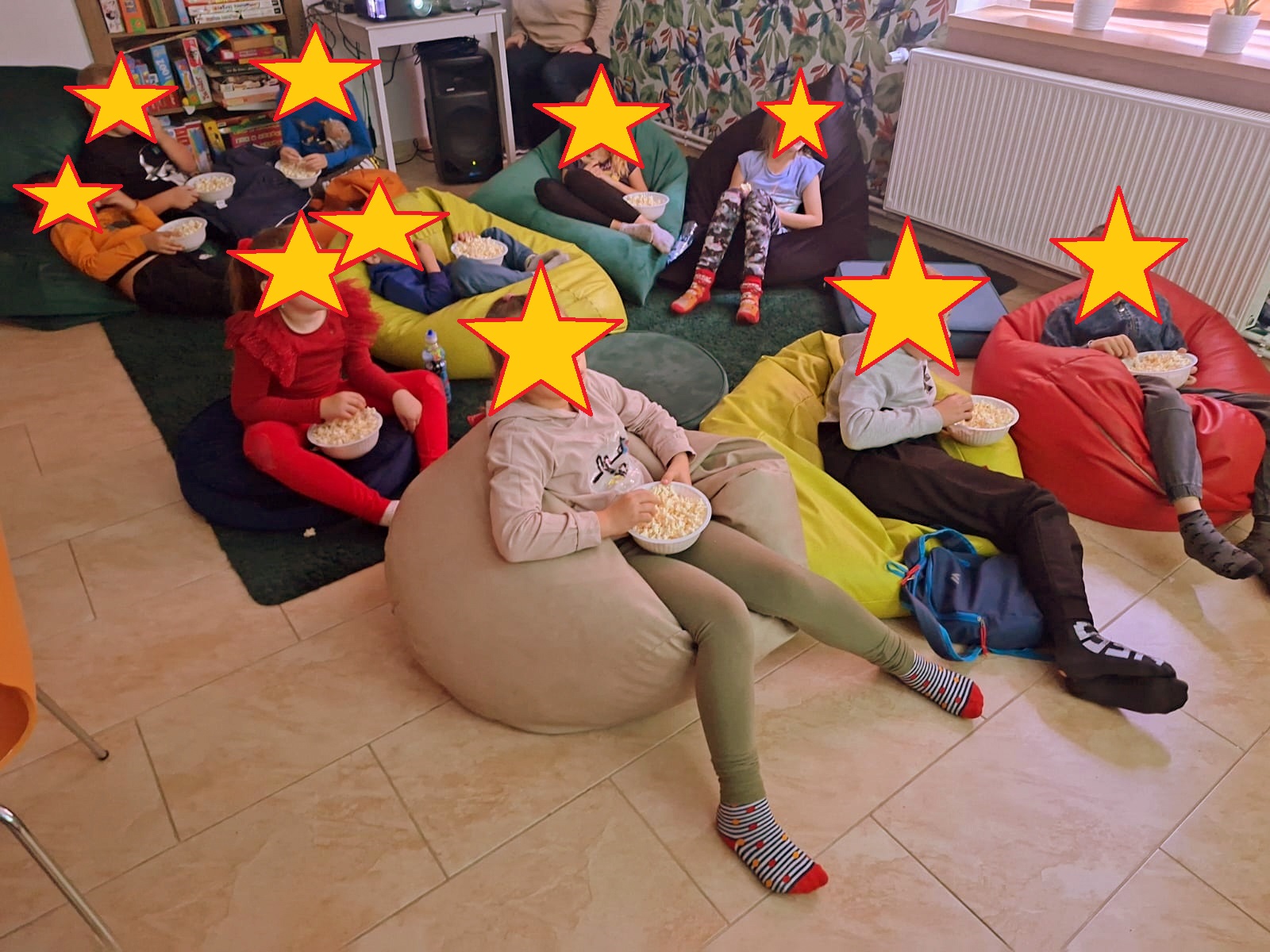 Grupa dzieci siedzących na pufach.