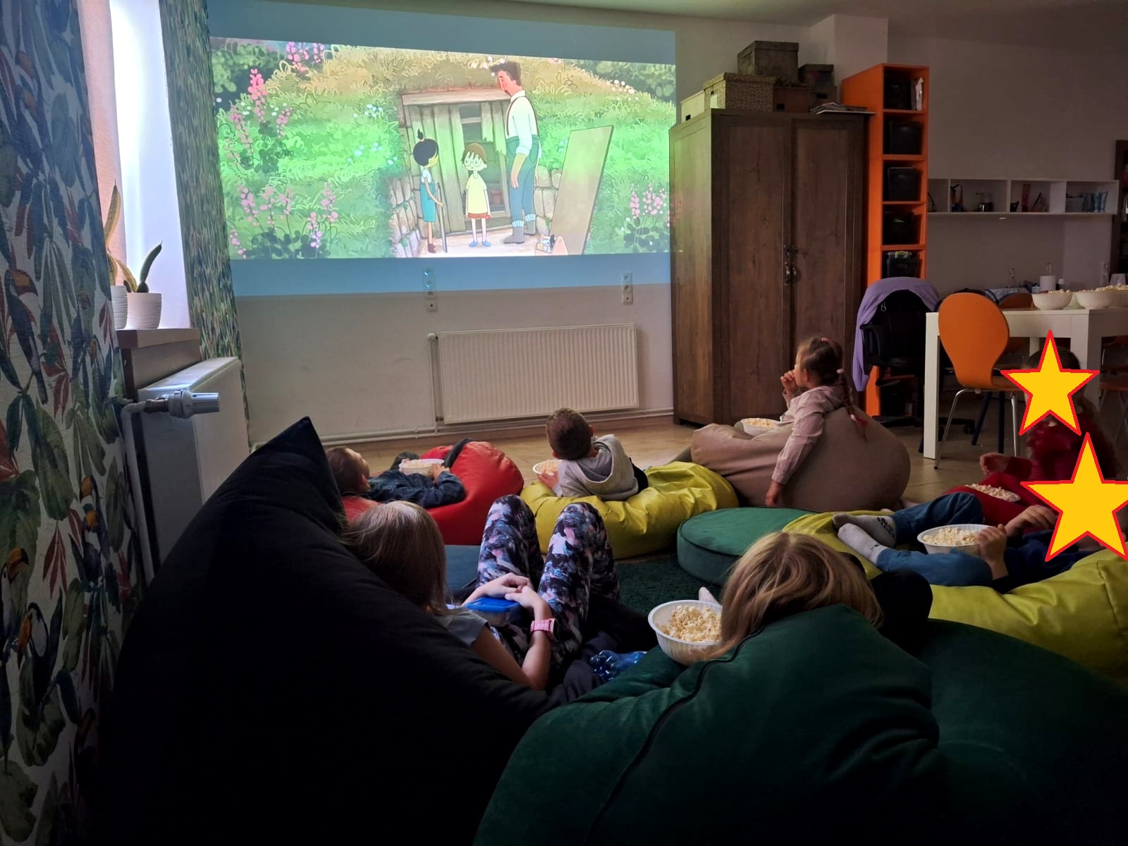 Grupa dzieci oglądających bajkę na dużym ekranie.