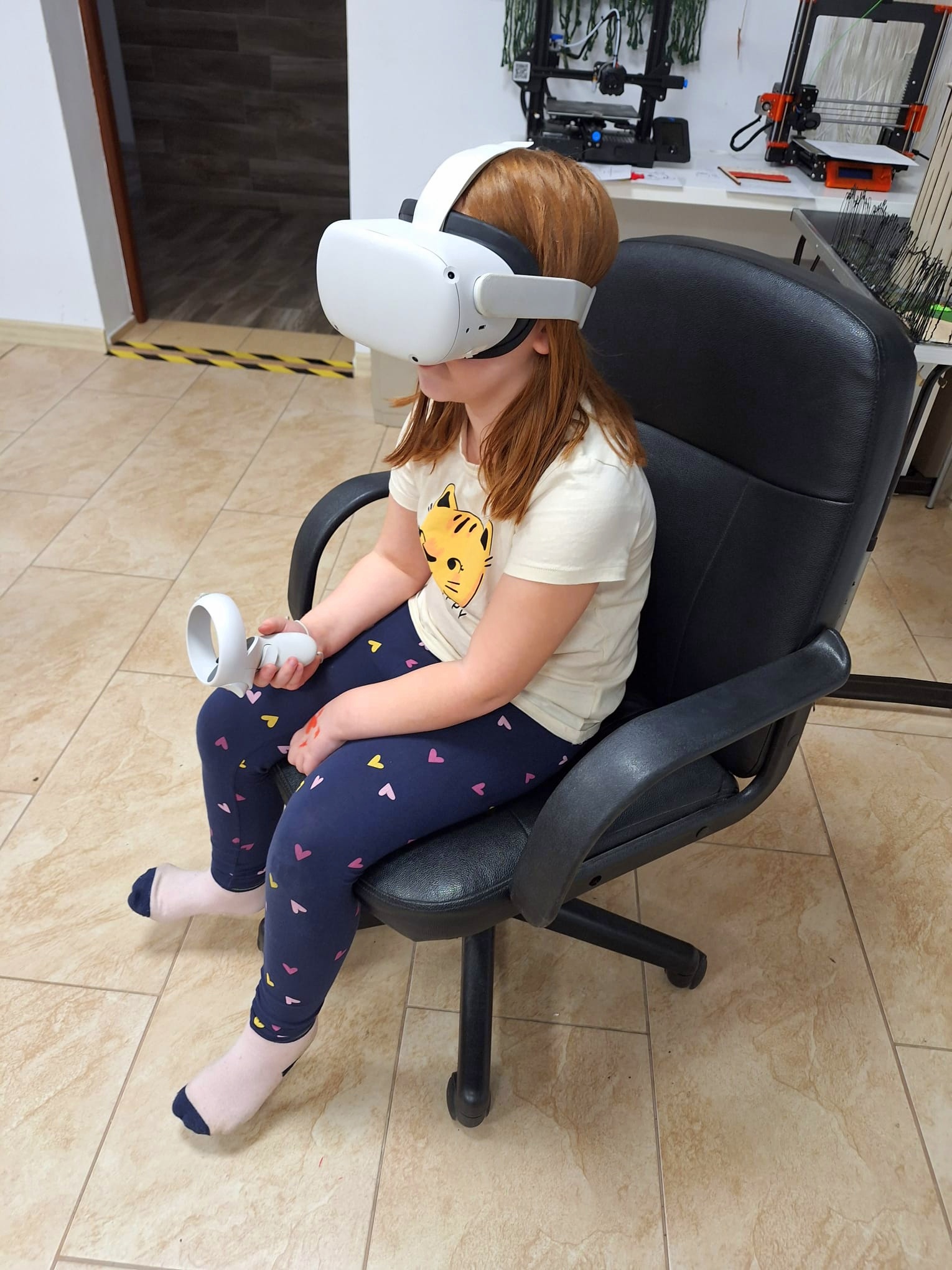 Dziewczynka siedząca na fotelu w okularach VR.