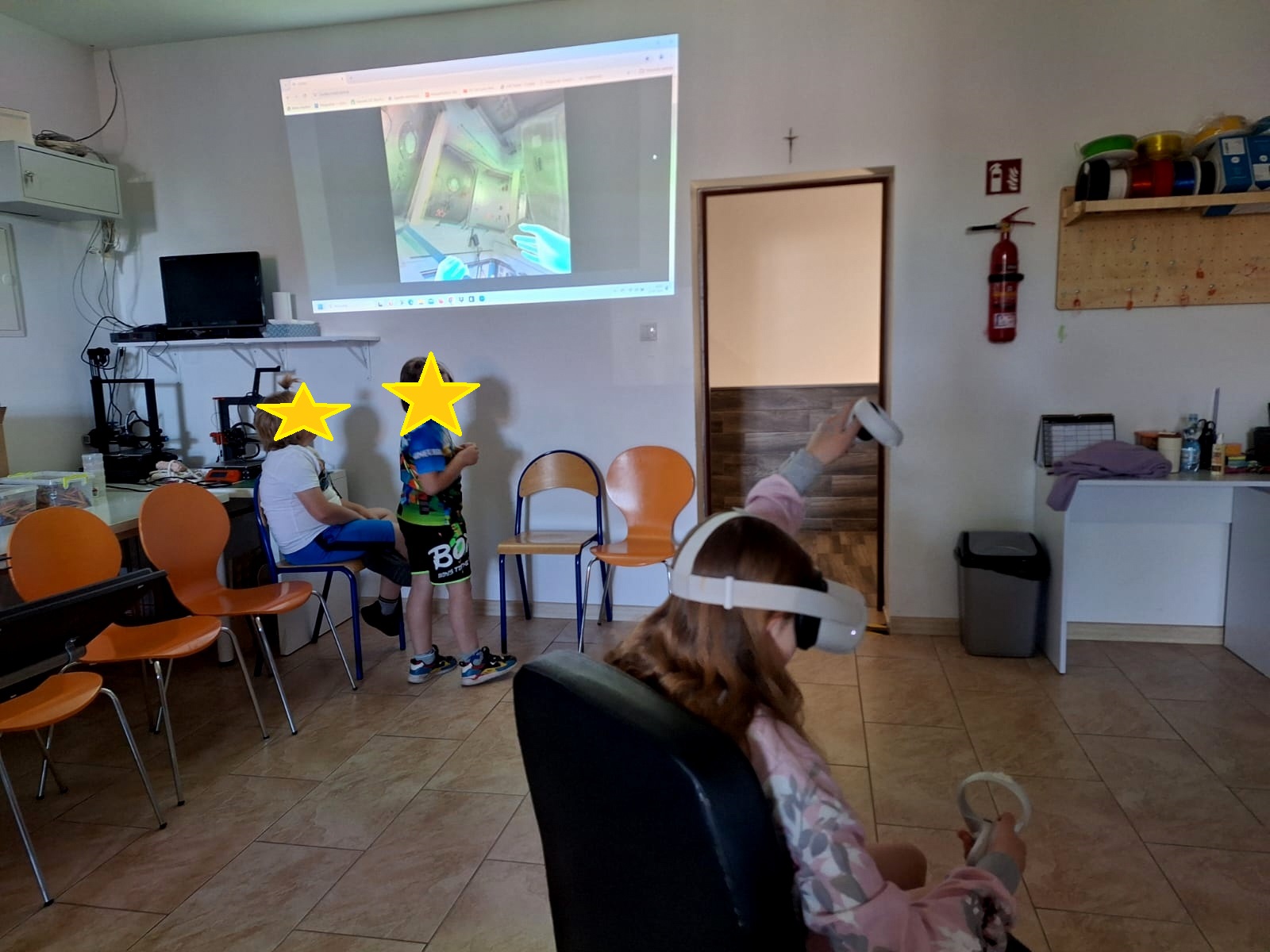 trójka dzieci w pracowni, jedna dziewczynka ma na sobie gogle vr