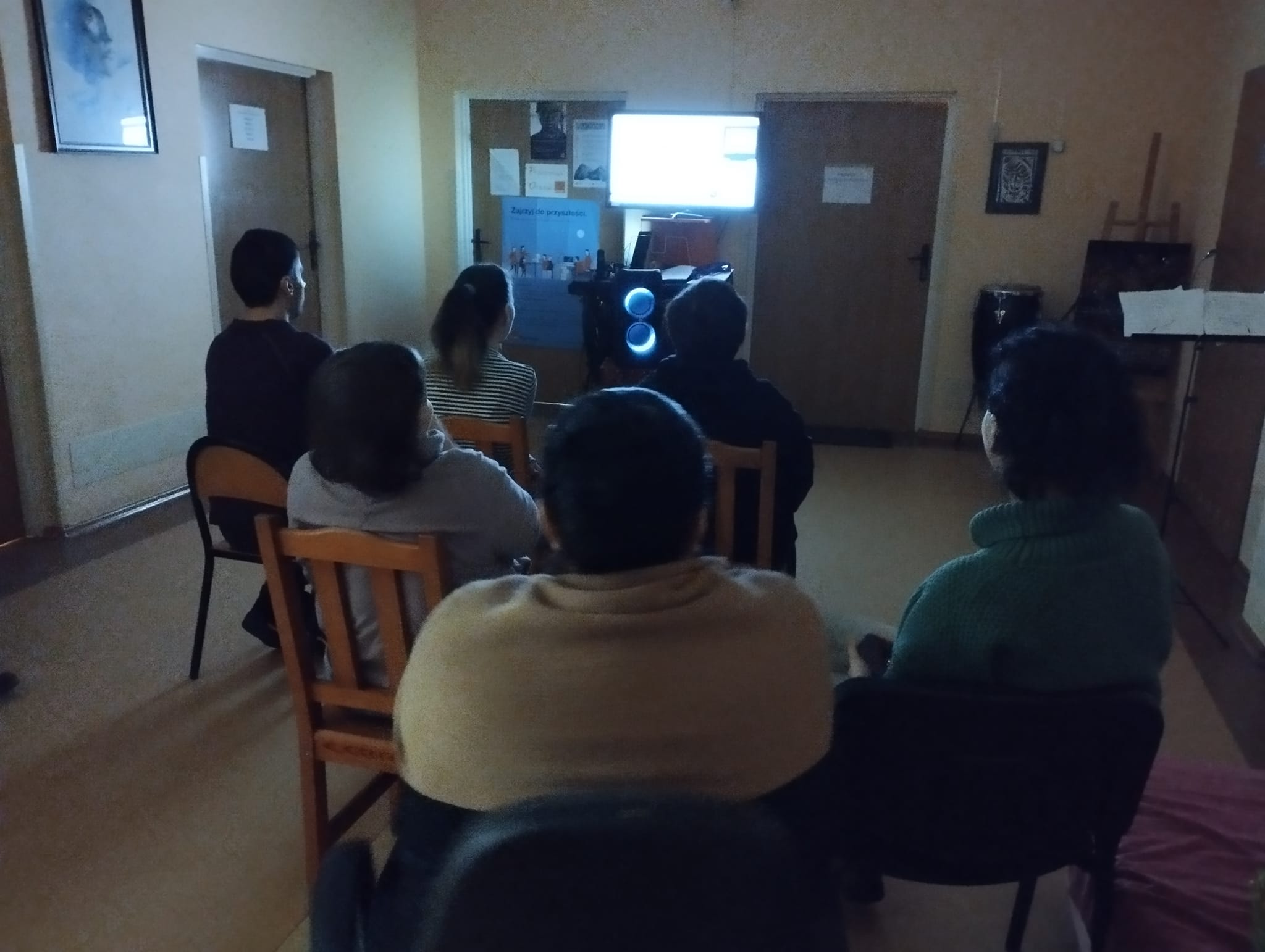Grupa osób ogląda prezentację na ekranie.