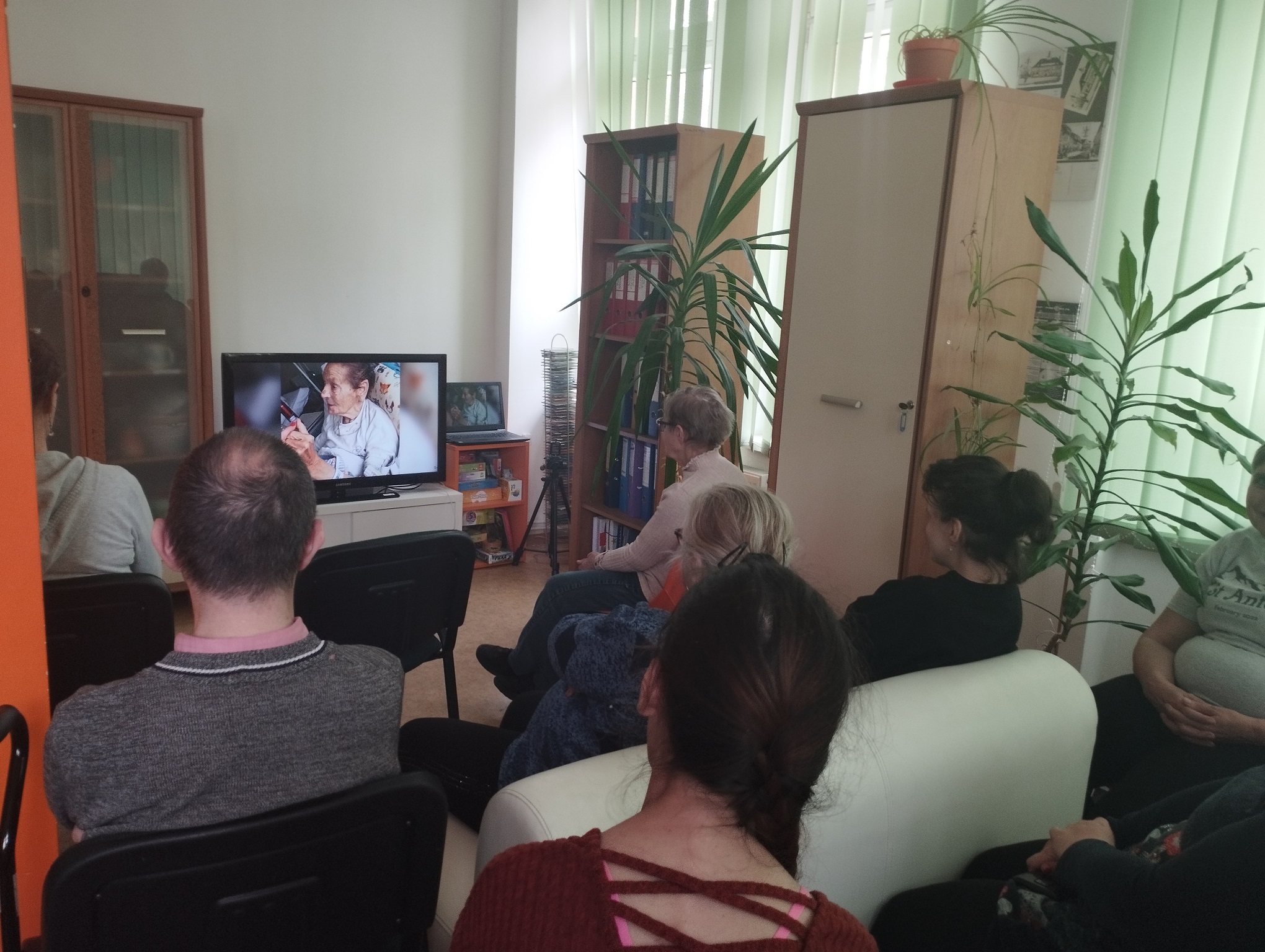 Grupa osób oglądających film na ekranie.