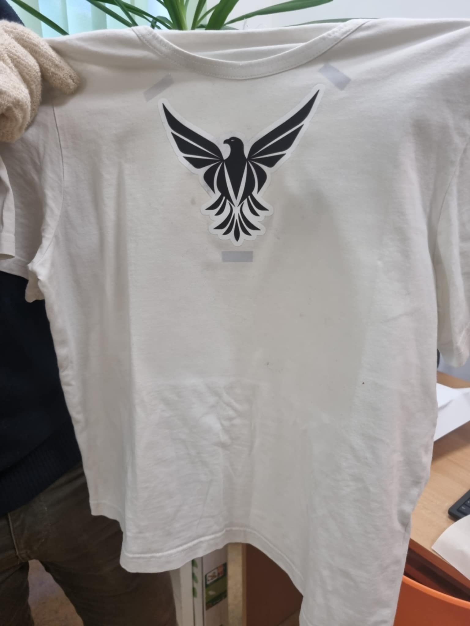 zdjęcie rąk trzymających koszulkę z nadrukiem orła