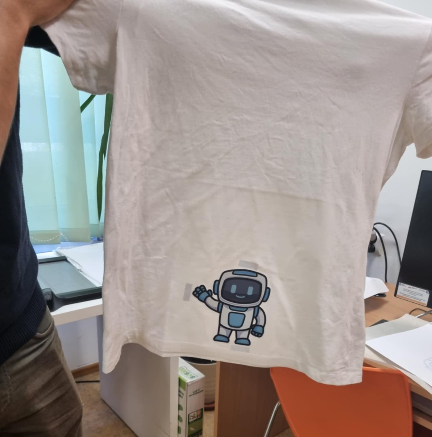 zdjęcie rąk trzymających koszulkę z nadrukiem robota