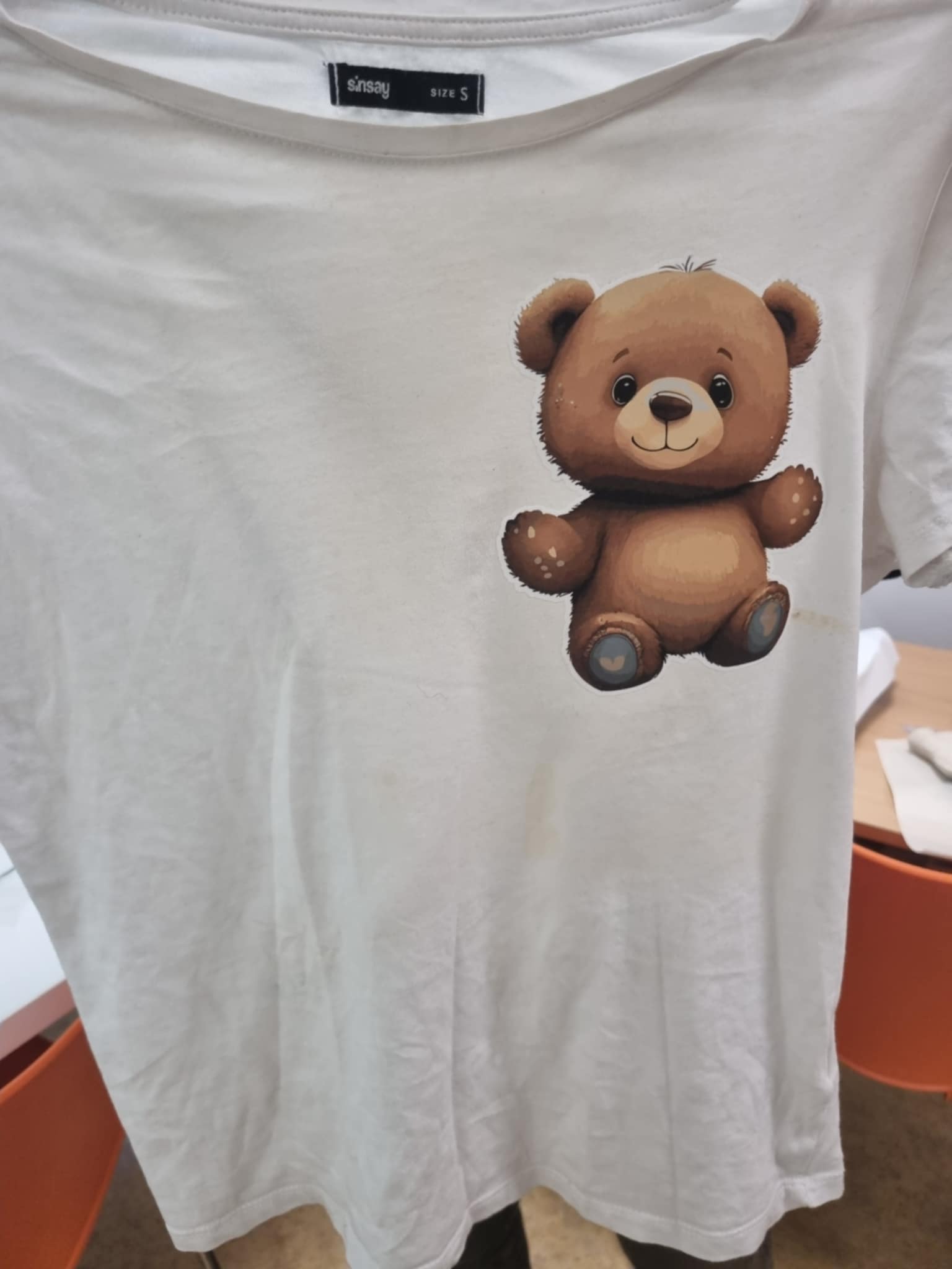 zdjęcie rąk trzymających koszulkę z nadrukiem misia