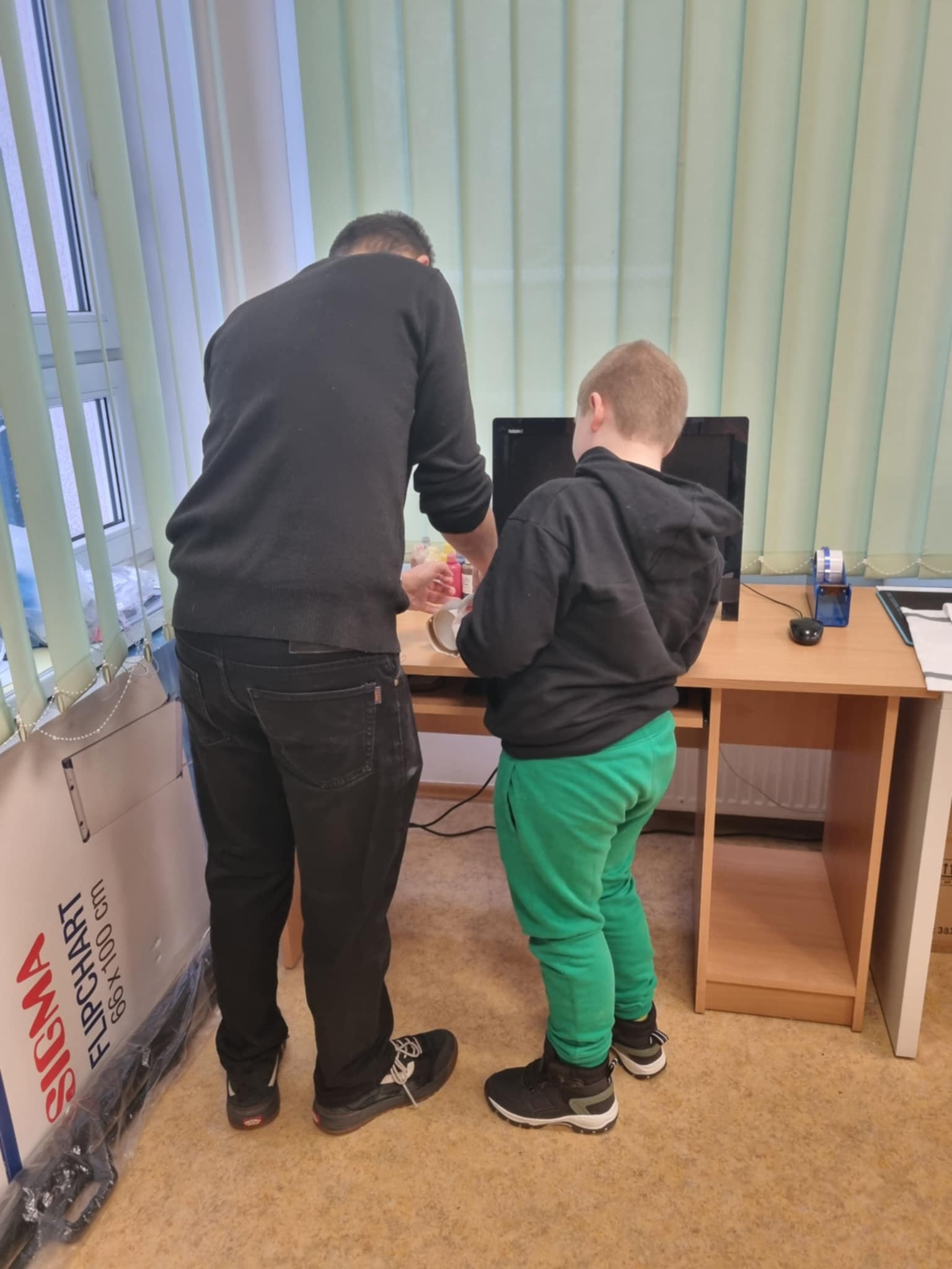 na zdjęciu chłopiec i prowadzący stojący tyłem do obiektywu