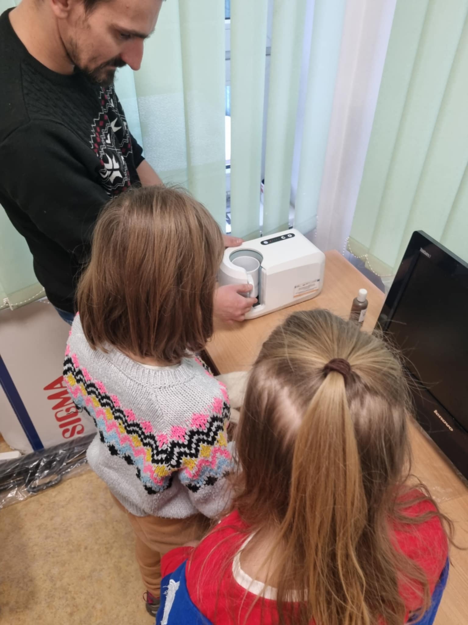 na zdjęciu dwie dziewczynki przy maszynie do nadruków