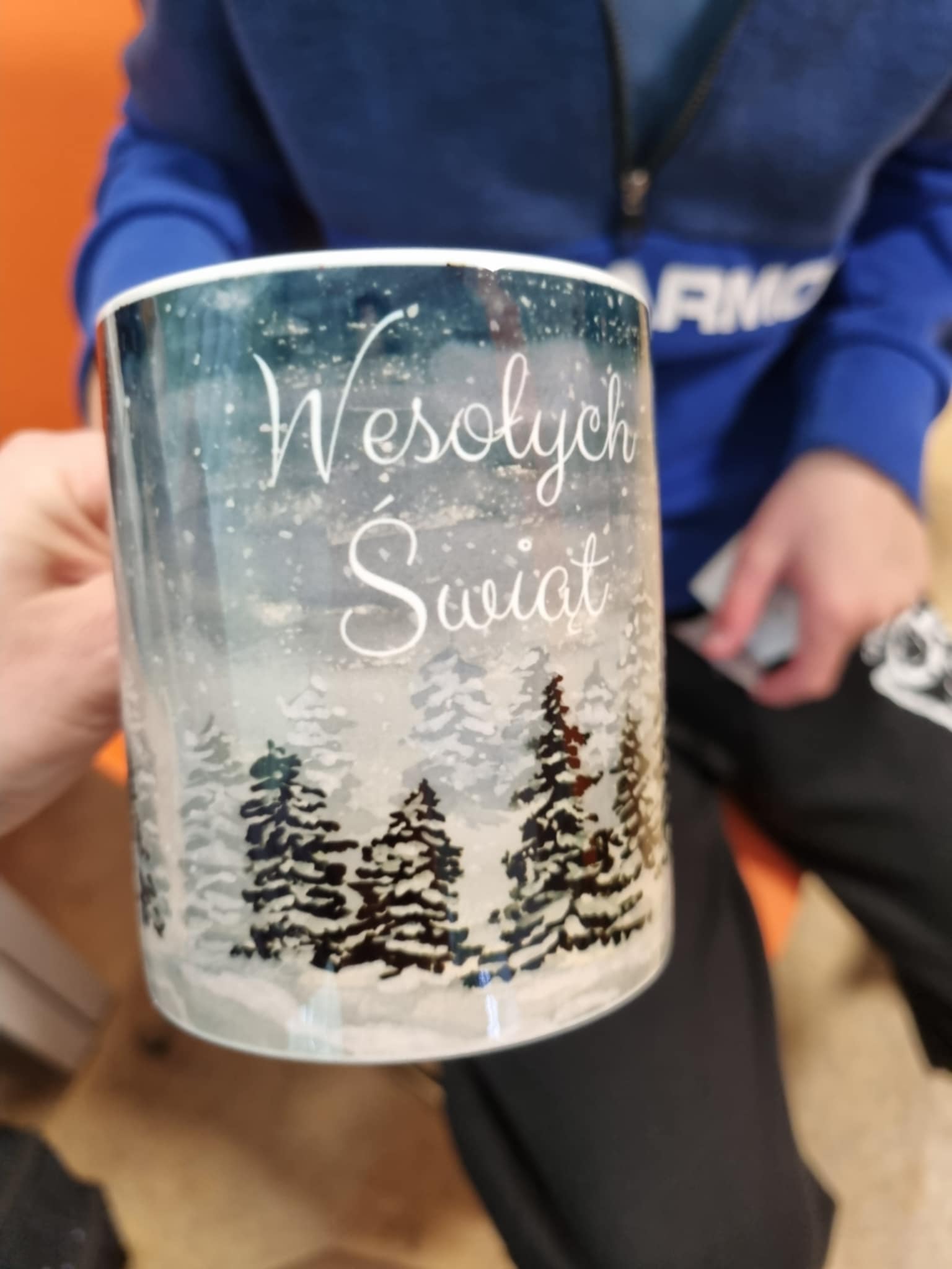 na zdjęciu osoba trzymająca Mikołajkowy kubek