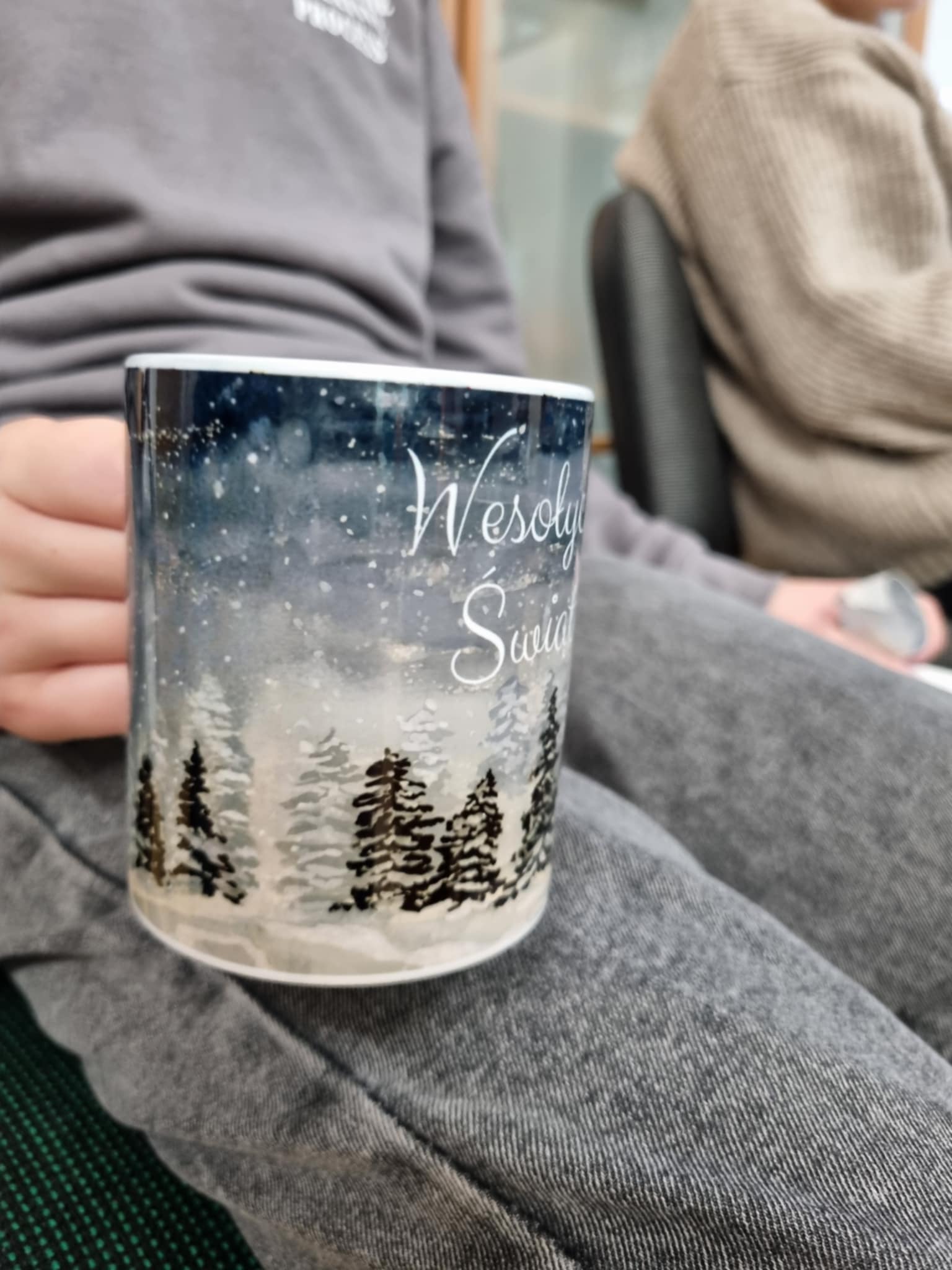 na zdjęciu osoba trzymająca Mikołajkowy kubek