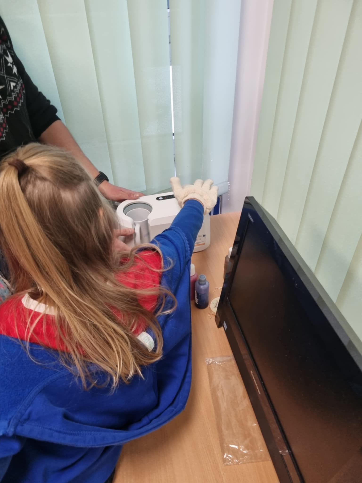 na zdjęciu dziewczynka obsługująca prasy do tworzenia nadruków na kubeczkach