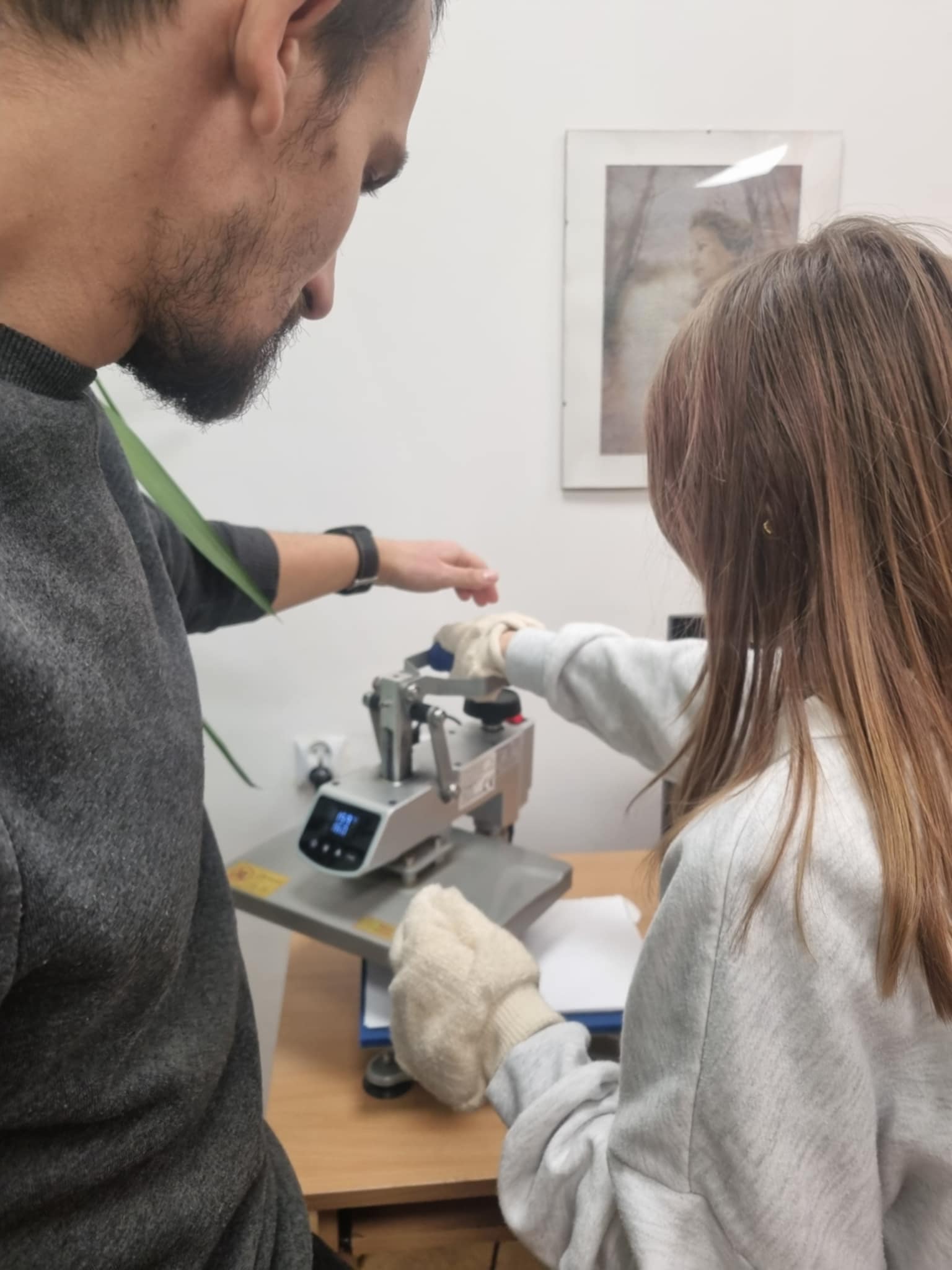 dwie osoby przy maszynie do nadruków