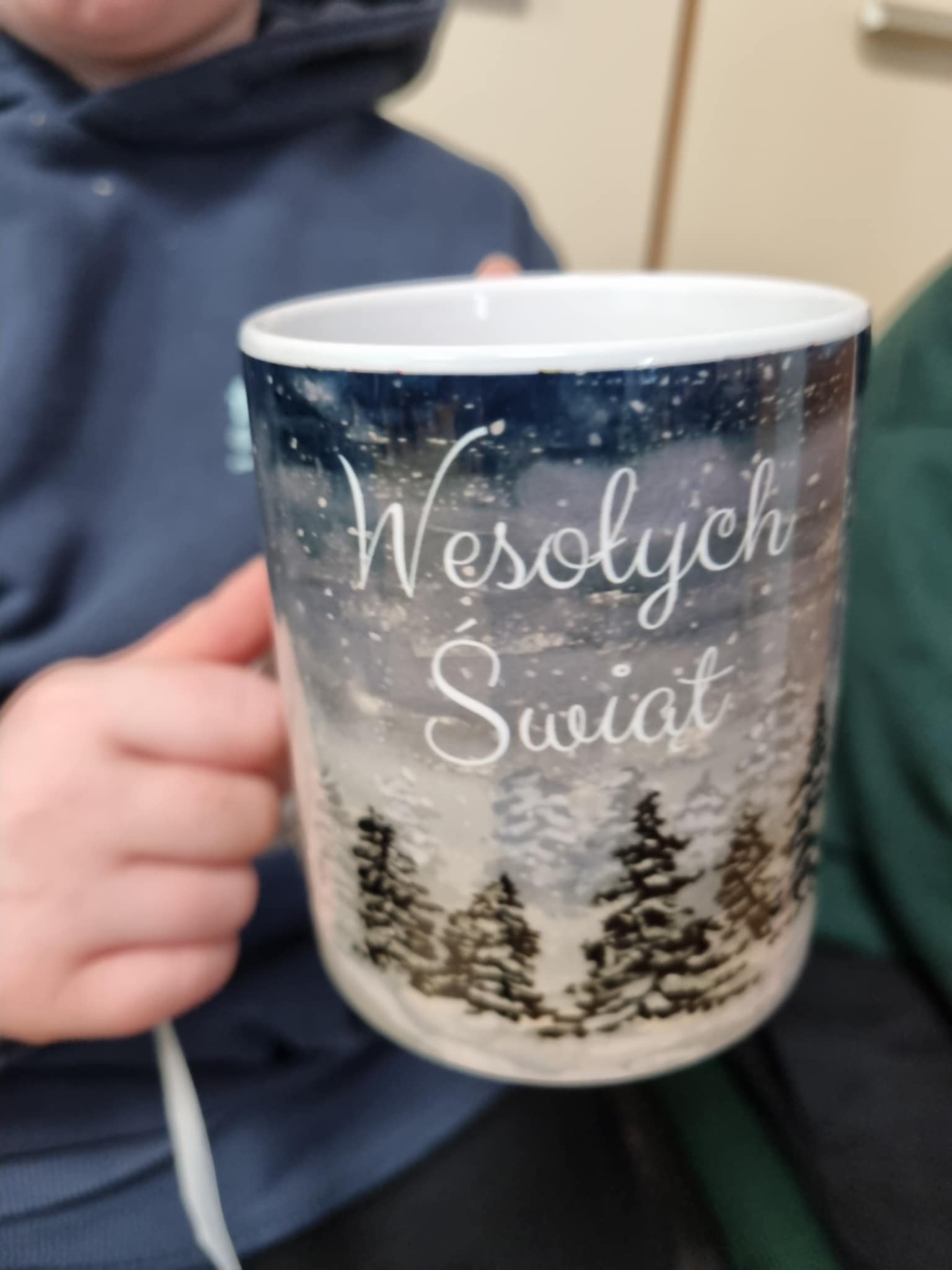 na zdjęciu osoba trzymająca Mikołajkowy kubek