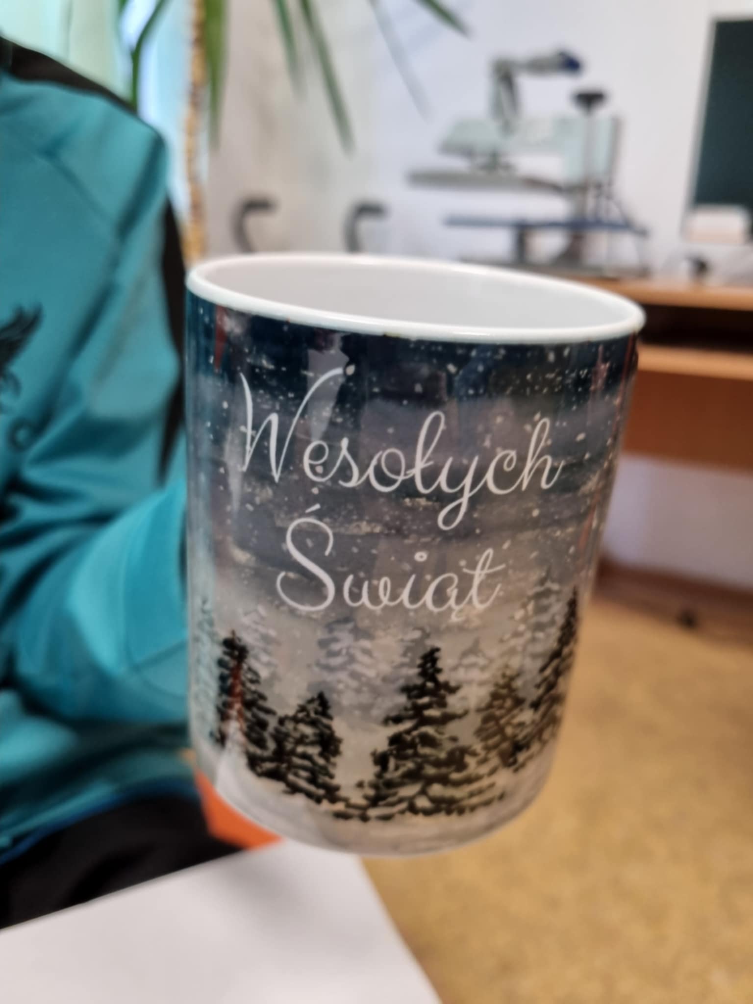 na zdjęciu osoba trzymająca Mikołajkowy kubek