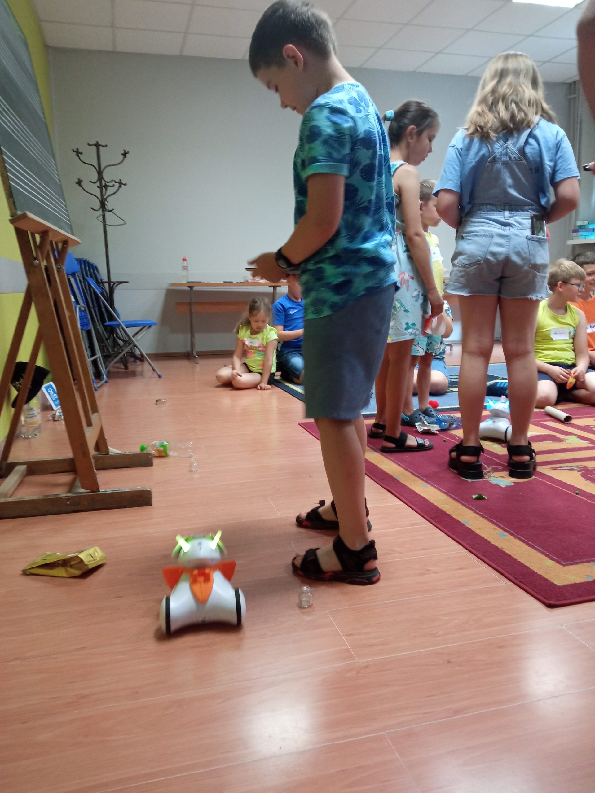 Kolorowe zdjęcie. Grupa dzieci pracuje z małymi robotami.