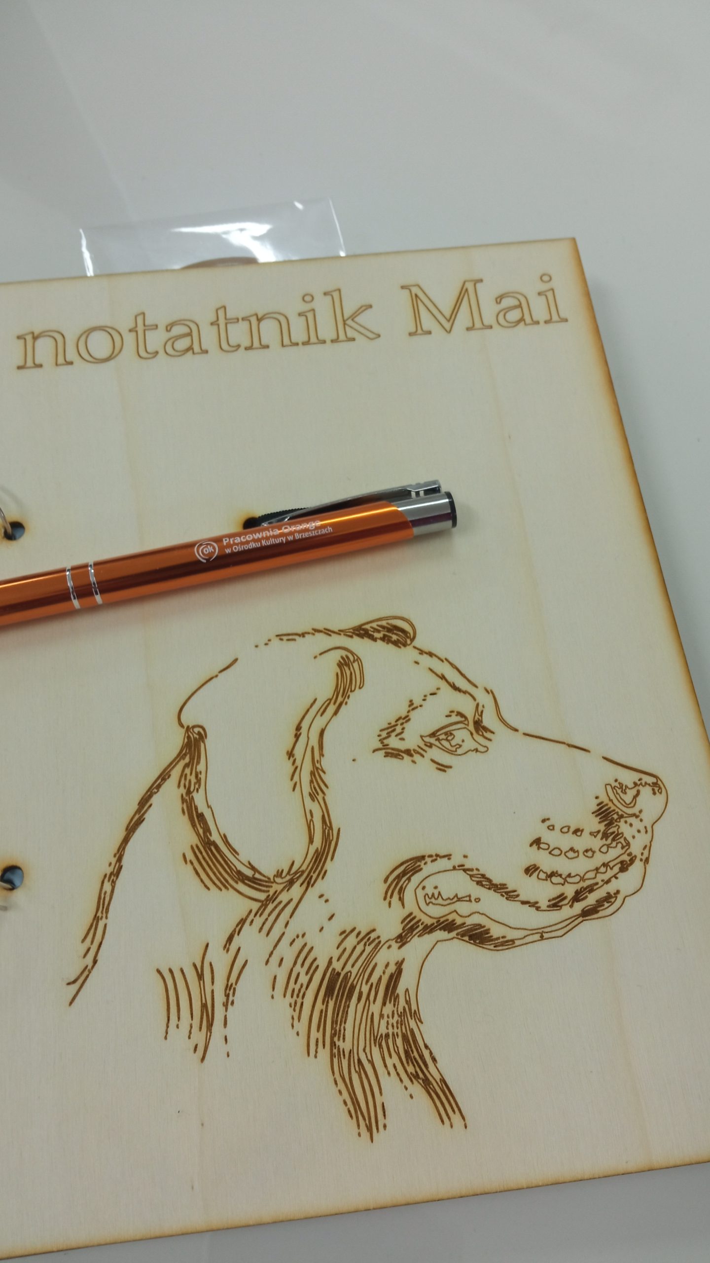 Zarys głowy psa, wygrawerowany na drewnianym notatniku