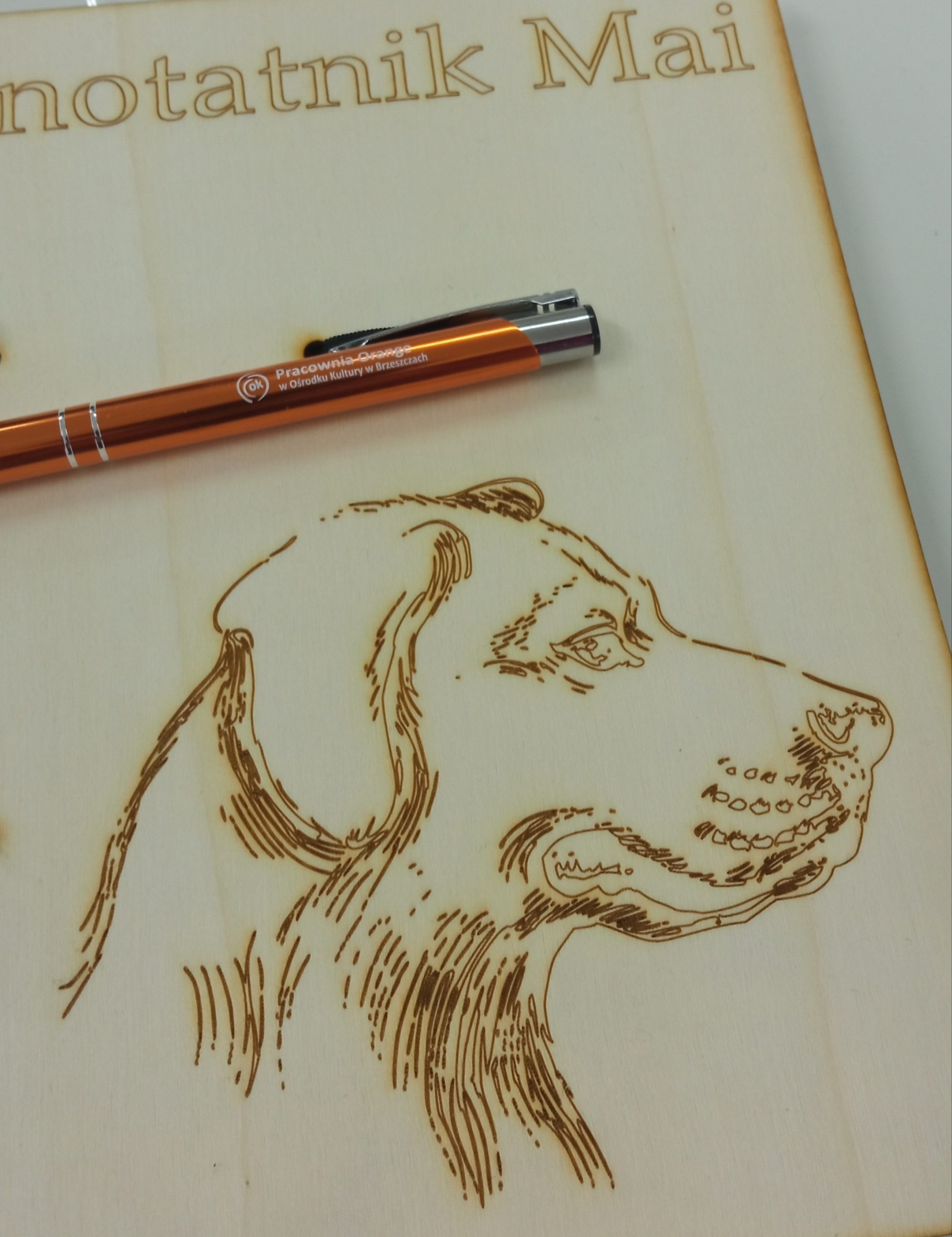 Zarys głowy psa, wygrawerowany na drewnianym notatniku