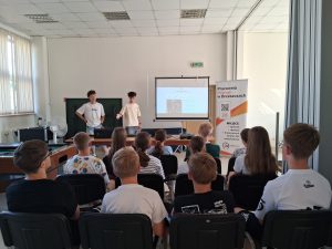 Grupa siedzących dzieci i młodzieży podczas zajęć.