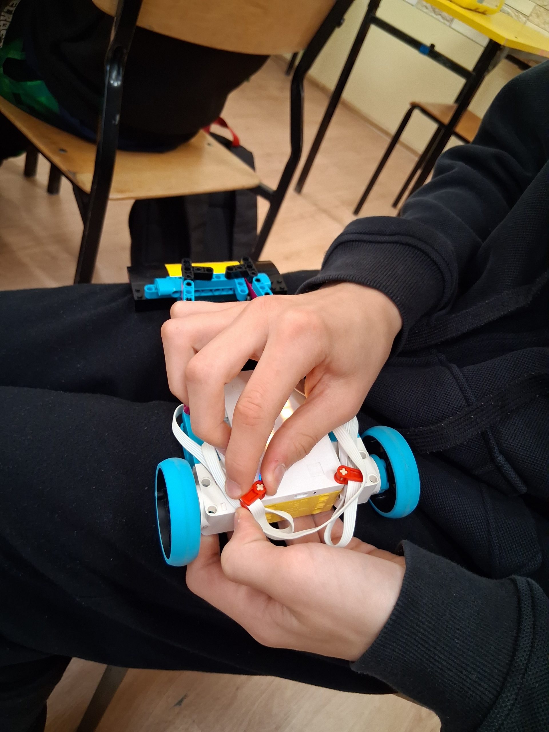 Zdjęcie dłoni podczas budowania robota z klocków.