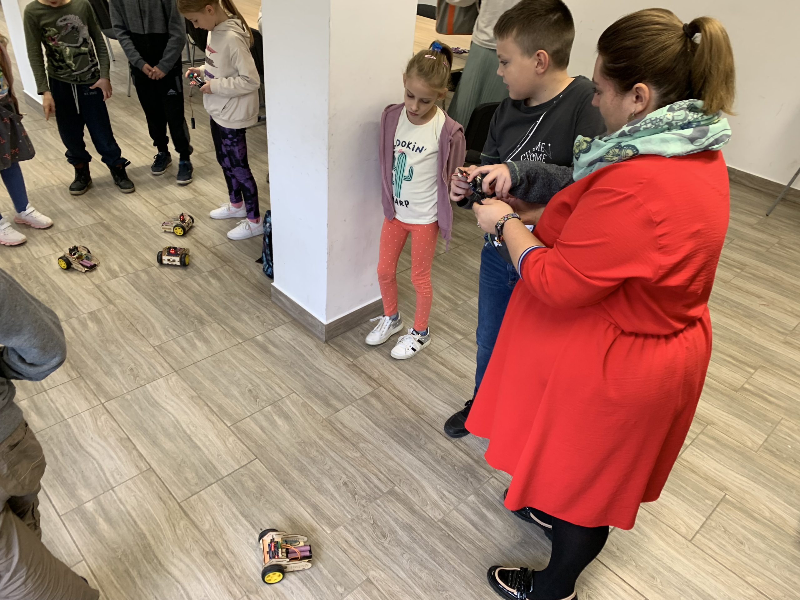Uczestnicy warsztatów ustawieni w kole patrzą na zaprogramowanego robota.