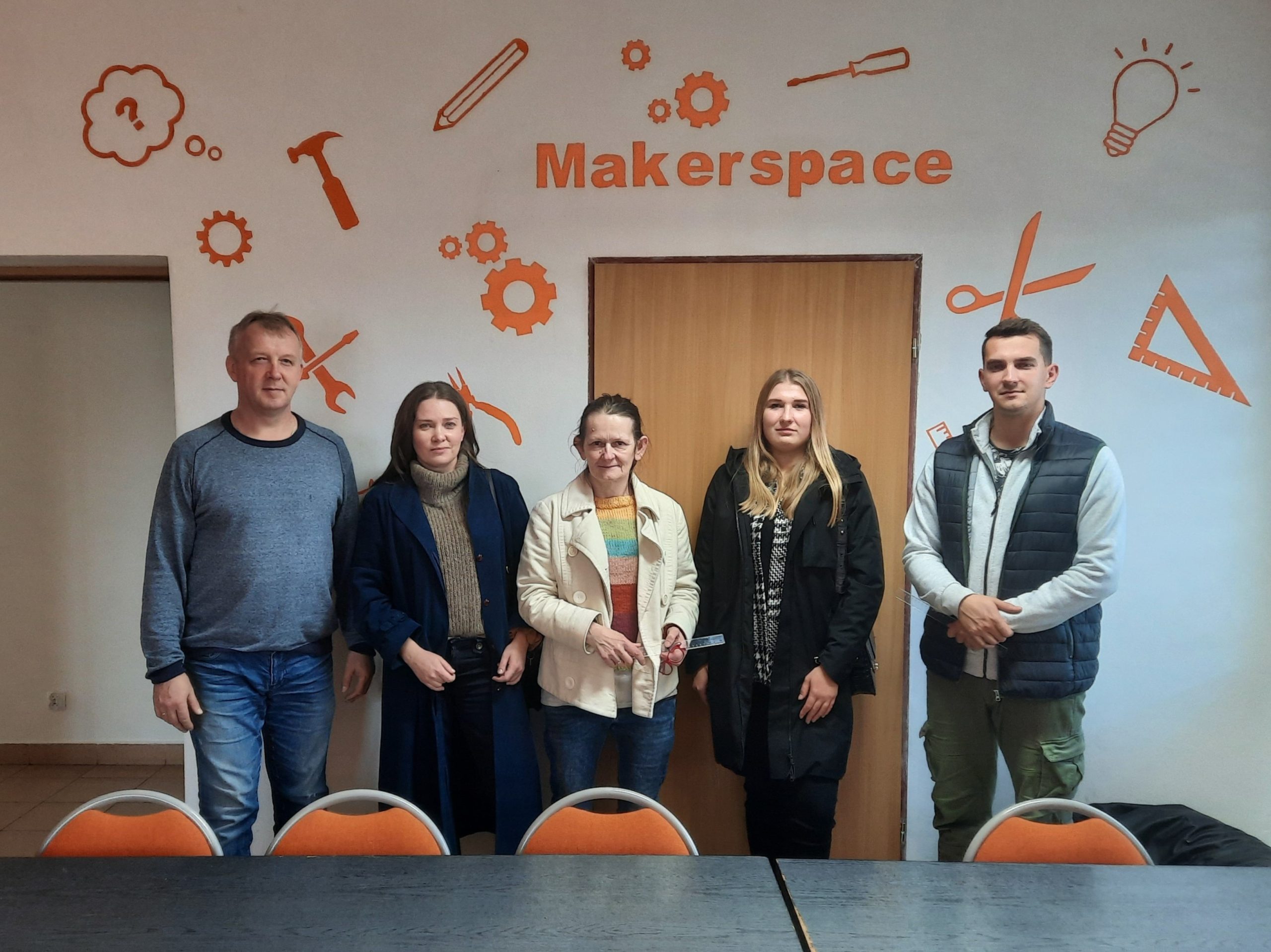 grupa pięciu osób na tle ściany z podpisem makerspace
